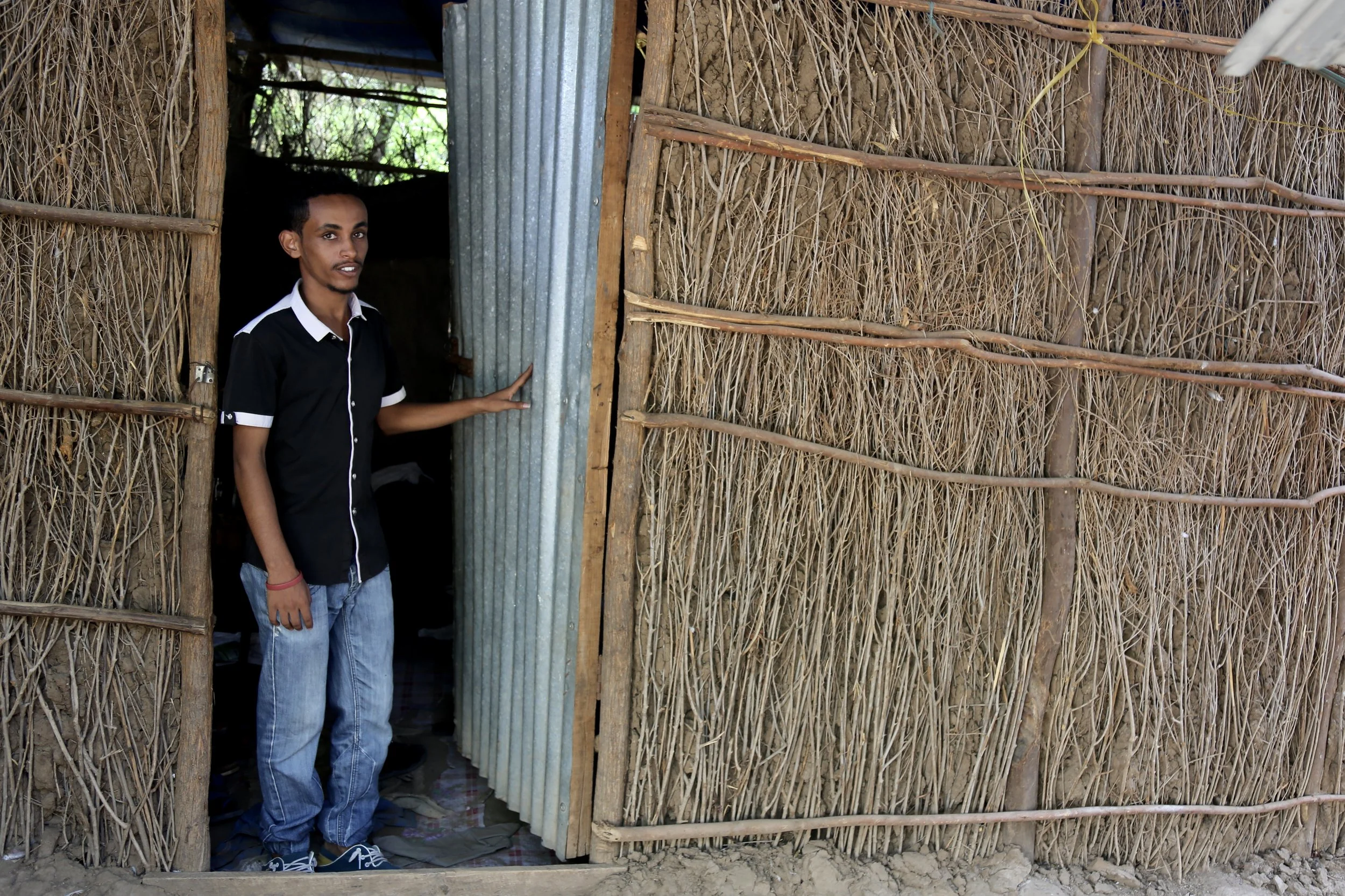 Nazrit stands at the entrance of the family home. After fleeing Ethiopia as a child, this shelter became another temporary chapter in a life shaped by movement.