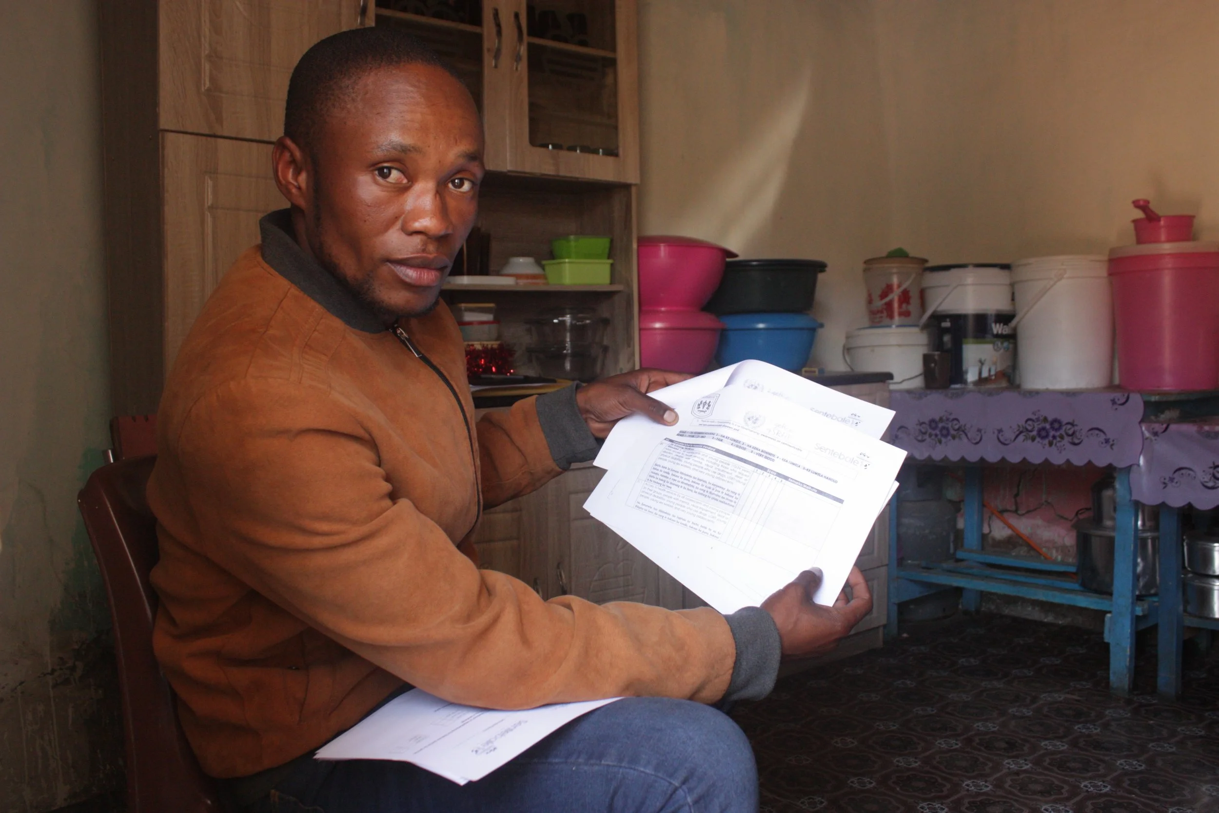 Pheto Kutumela holds completed scorecards used to evaluate healthcare access and service delivery in remote mountain communities. Beyond advocacy training, participants in the programme learn to monitor local facilities and engage policymakers over g