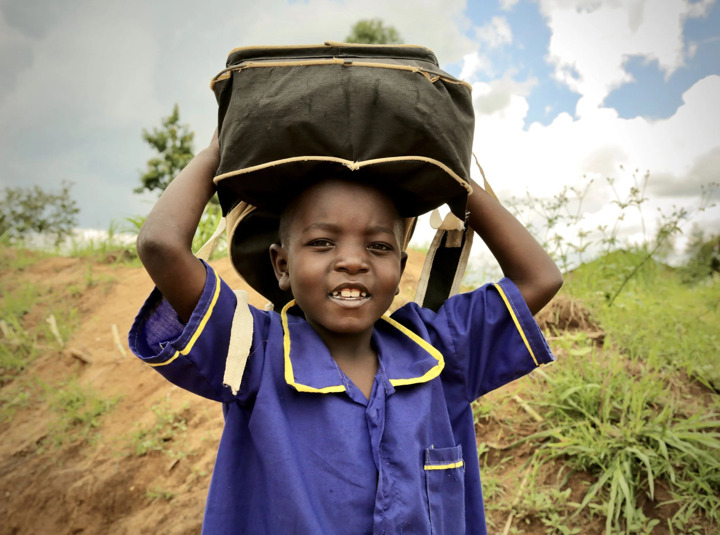 A pupil carries a schoolbag and a small container on his head in Kakamega County, Kenya. Children frequently help transport water home for cooking, cleaning and drinking, often making several trips each day.