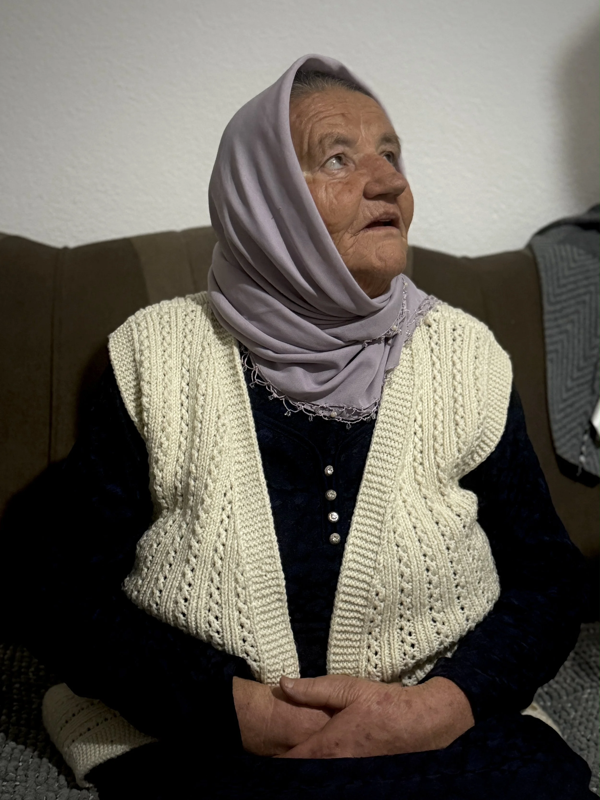Saliha Osmanović seated in her living room in Dobrak, Bosnia and Herzegovina.
“I lost two sons and a husband. I returned here alone,” she said. She chose to come back because living there keeps her closest to them.
