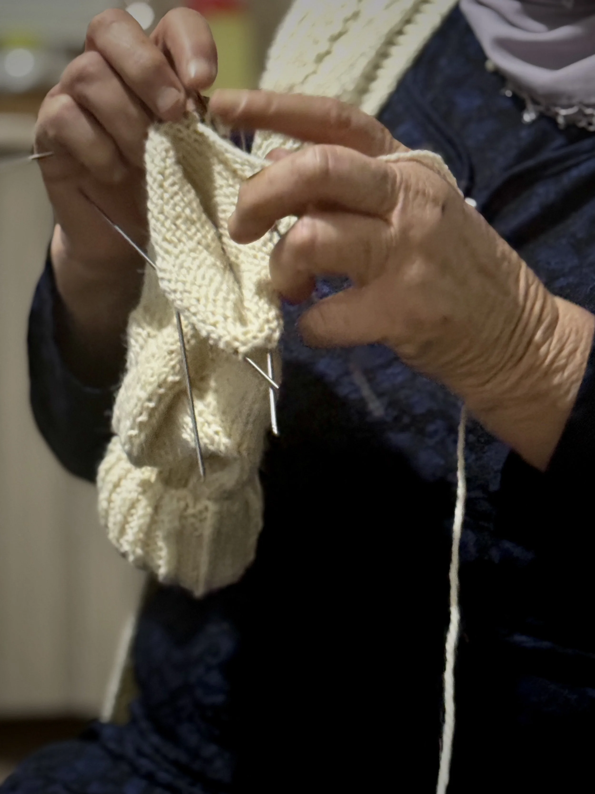 The hands of Saliha Osmanović knitting at home in Dobrak, Bosnia and Herzegovina.
She knits winter socks to help make ends meet. Each pair takes several days to complete, filling long hours with routine and work.