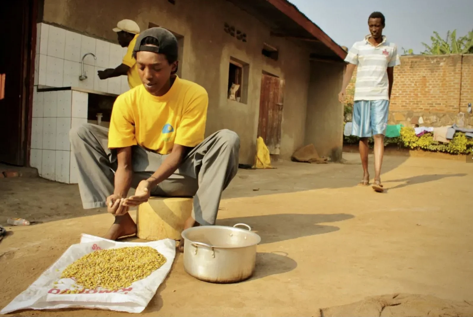 A young Burundian refugee, Tresor Niyingabo,  prepares beans outside the Kigali compound where activists, former protesters and artists lived together in exile. Daily routines such as cooking and cleaning were shared collectively among residents as t