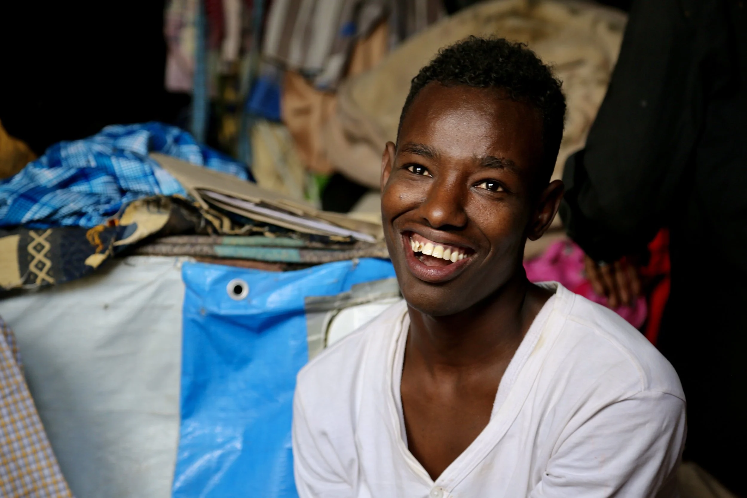 A young man from South Sudan spends time in the shop, exchanging jokes in English and Kiswahili with others who gather there.