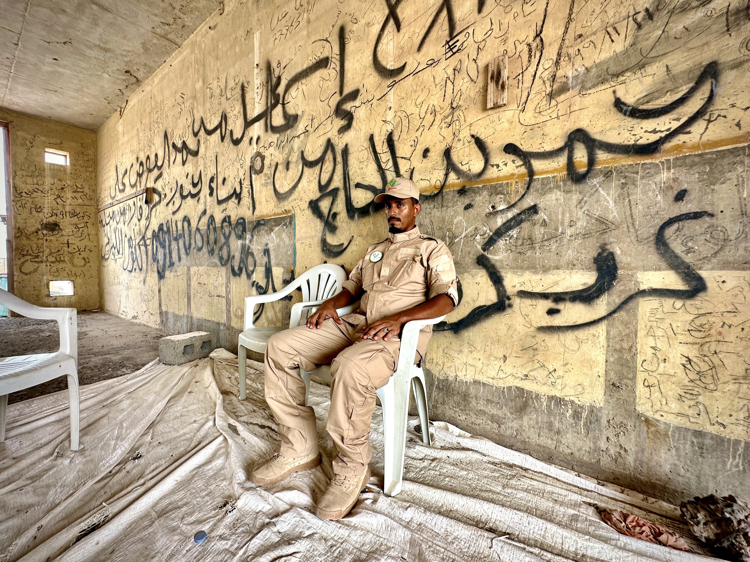 Project Masam Team 24 Leader Jalal Ama'abd Amer rests inside a bomb-damaged building now used as a control point during clearance operations at Aden International Airport. Deminers often pause during extreme heat before returning to careful search wo