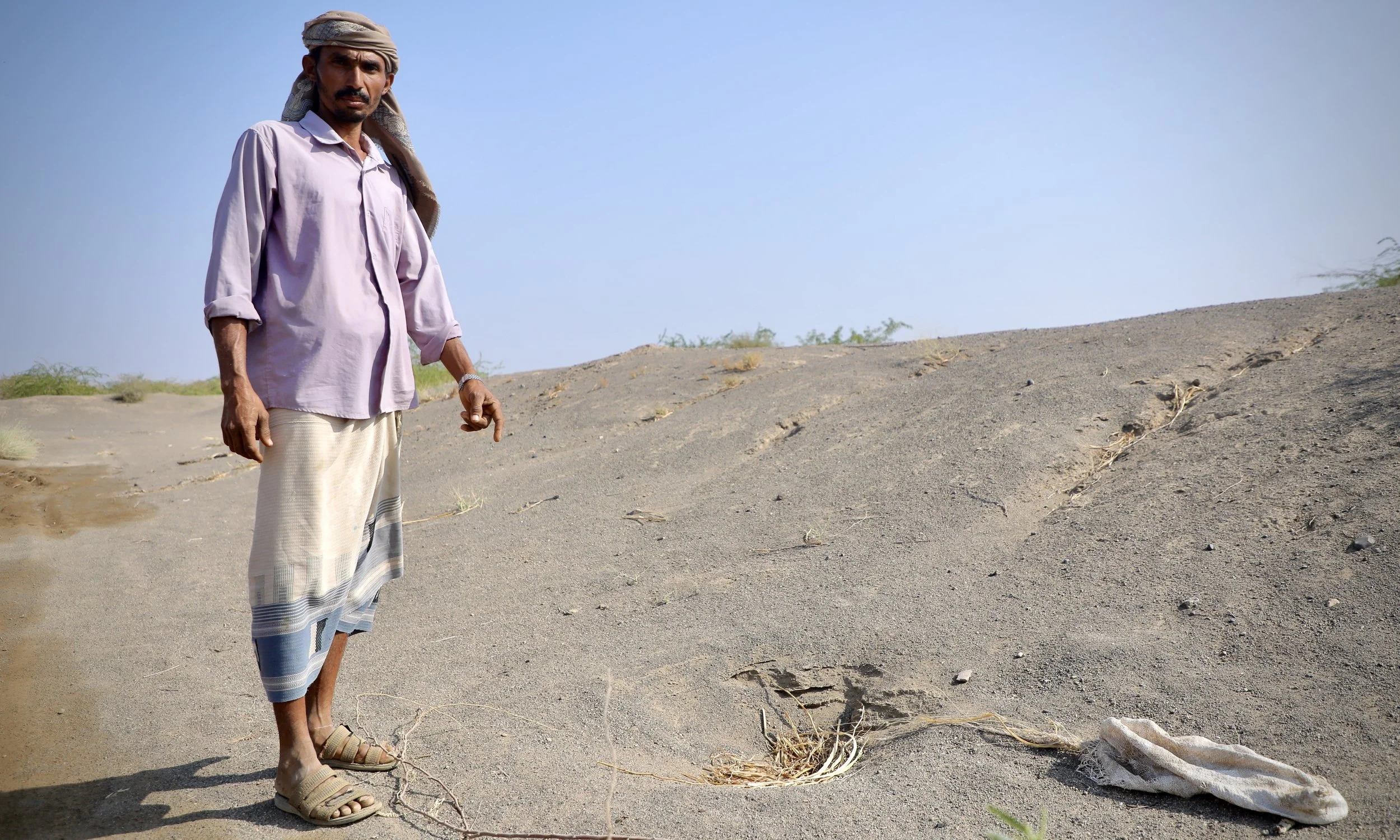 Amar points to a mound where mines were recently found and cleared. He continues to discover contamination on his land as clearance progresses.