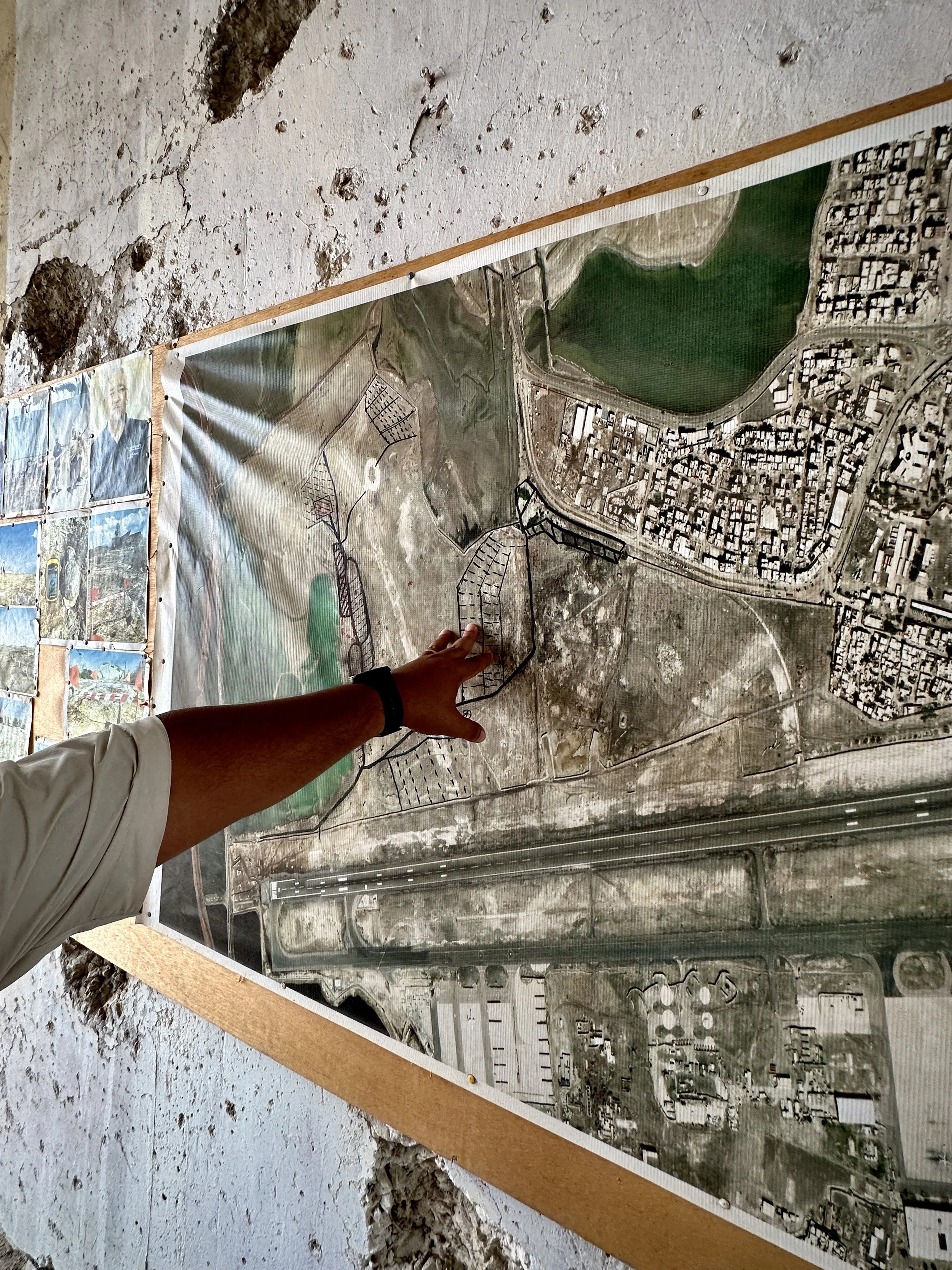 A supervisor points to a clearance map marking searched sectors and hazardous areas at Aden International Airport. Detailed mapping is used to track progress and guide deminers working across former battlefield terrain still contaminated by wartime e