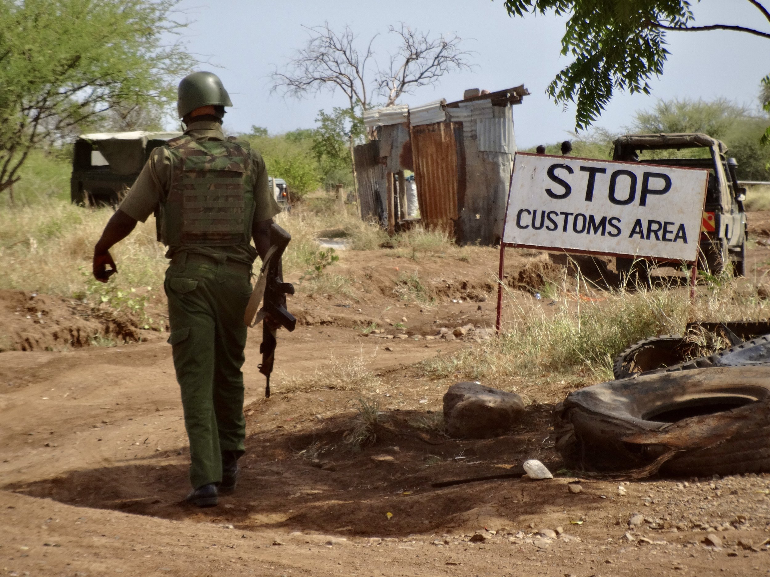 A Kenyan security officer walks near a “Stop Customs Area” sign at the Nadapal border crossing, the main point of entry between South Sudan and Kenya.