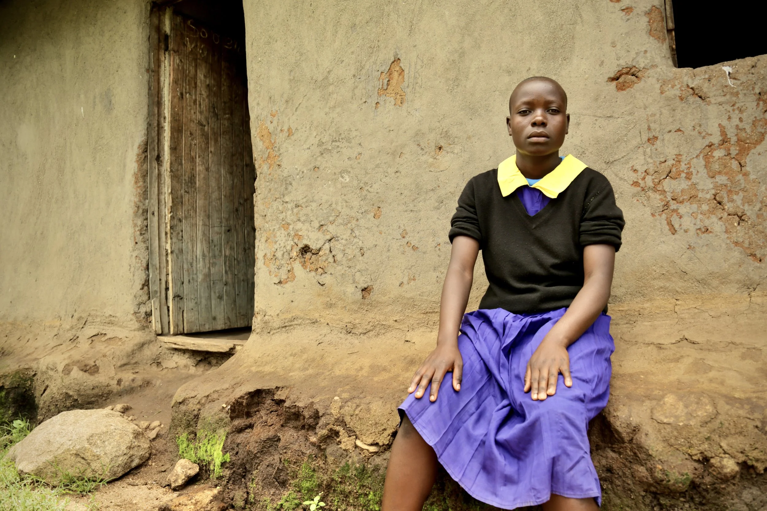 Chris Figmitis, 14, sits outside her home in Kakamega County, Kenya. Chris studies at Shinyunzu Primary School and lives with her father and grandmother in a household of three. When asked about water availability at school, she stressed the importan
