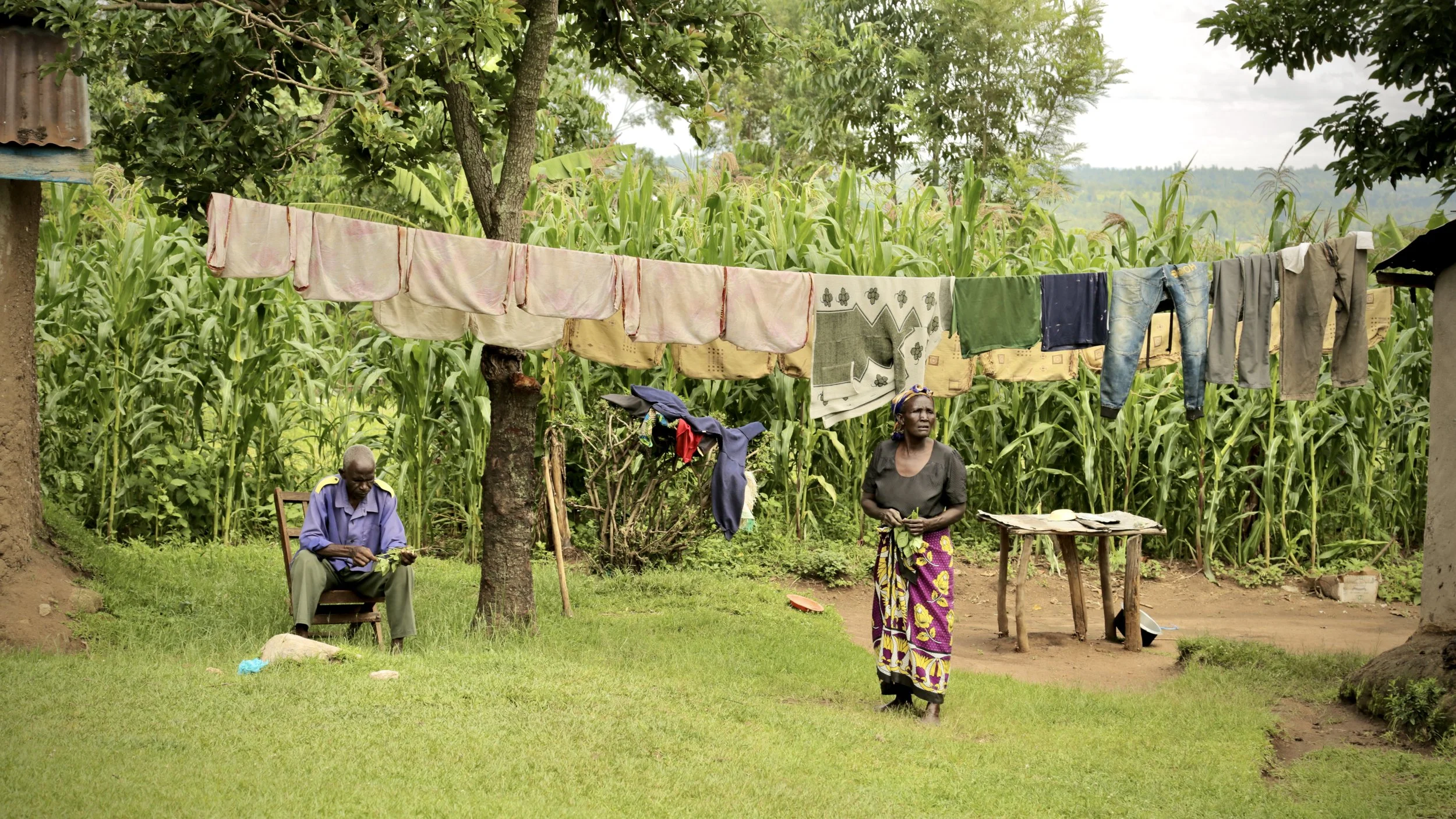 Residents stand outside their home in Kakamega County, Kenya. Families across the region often manage limited water supplies used for drinking, cooking, cleaming and livestock, while balancing farming, childcare and education.