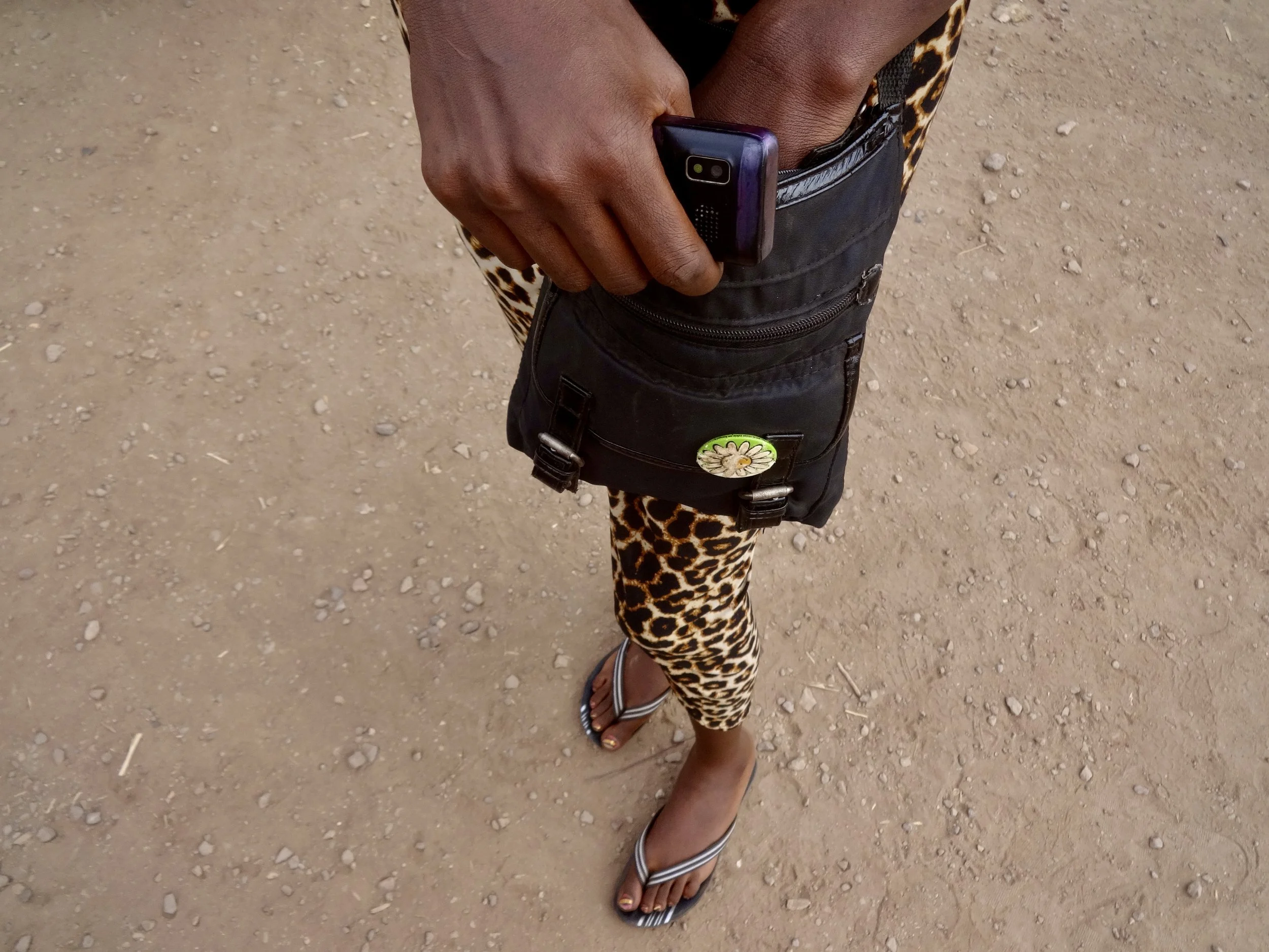 Randa checks her phone while waiting. She was attempting to stay in contact with her family, who were expecting her in Kakuma.