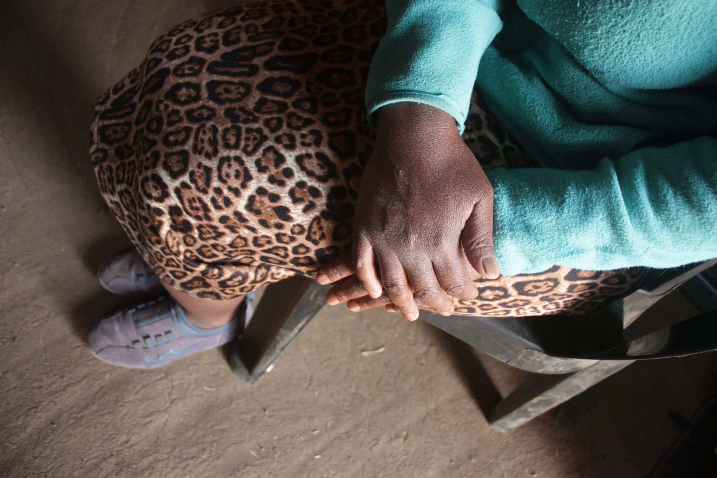 Palesa rests her hands in her lap while speaking about caring for her daughter inside their stone house in the mountains of Thaba Moorosi, Lithipeng,