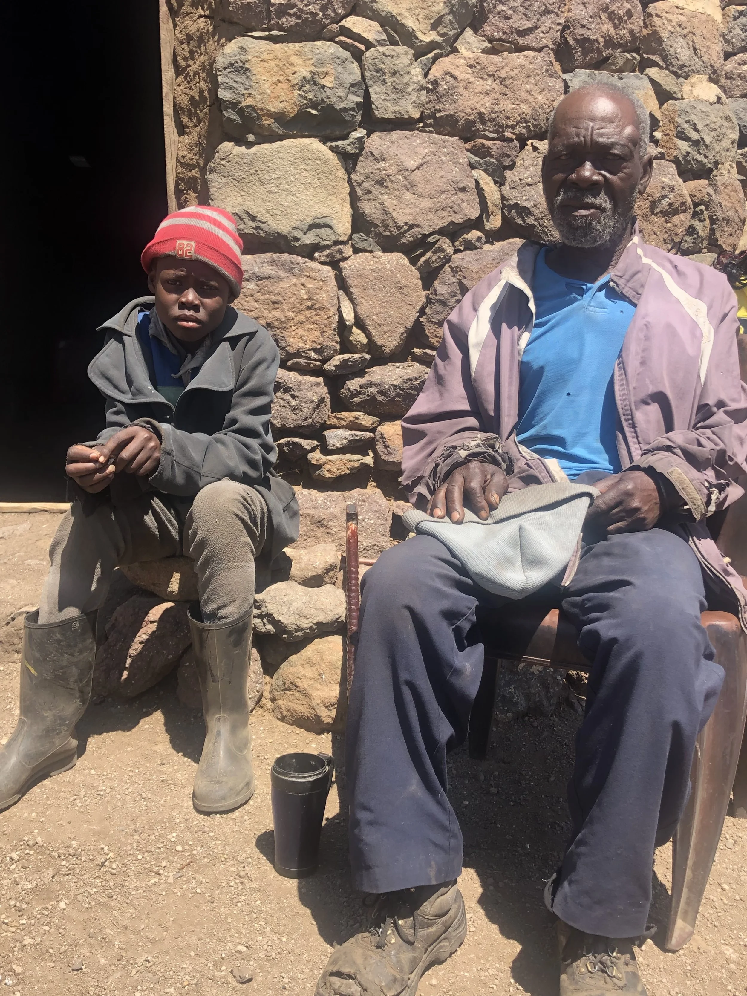 Bokang Khera sits beside an older relative outside their home in Thaba Moorosi. Though the exact family relationship was unclear, Bokang referred to him as “uncle.” Living together in isolation, Bokang helped herd cattle while the older man provided 