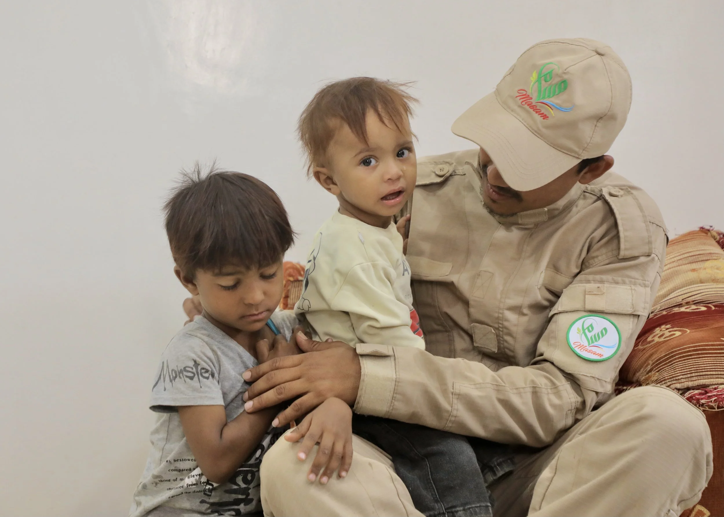 Sami sits with his children after returning home from work.