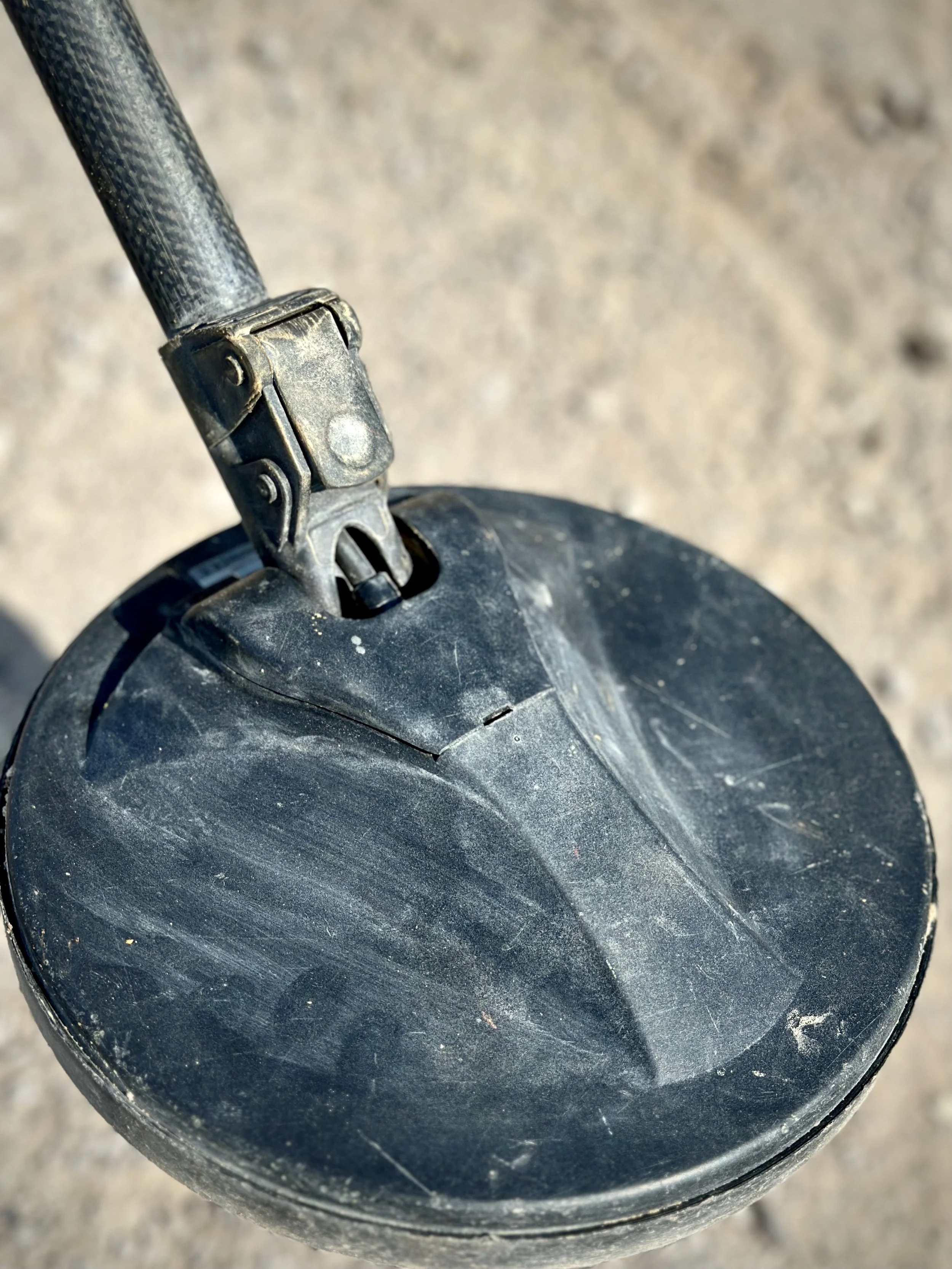The search head of a metal detector rests on the ground during mine-clearance operations at Aden International Airport. Deminers sweep slowly across difficult terrain where metal fragments, construction debris and war remnants can complicate detectio