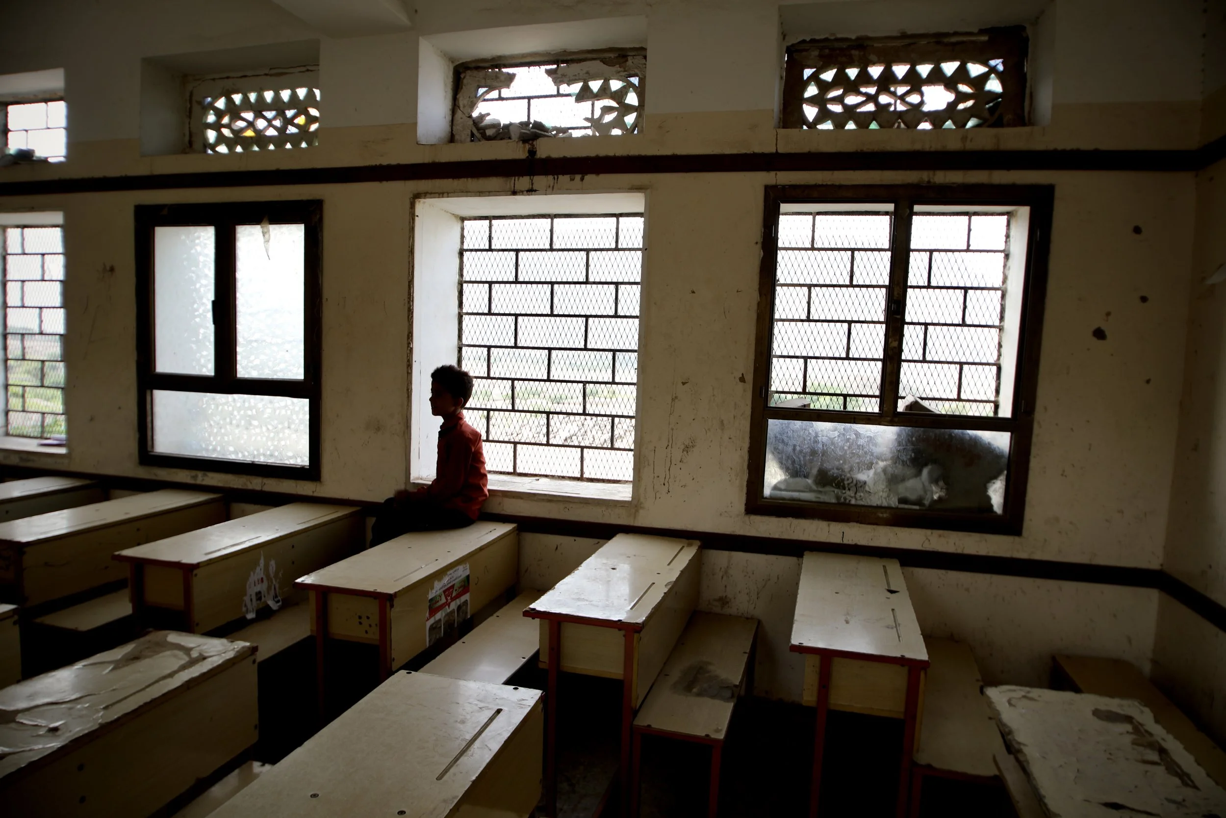 Marwan Al Barakani, 10, sits inside a damaged classroom at Al Shaab School in Jabal Habashi district, Taiz governorate, Yemen. Residents say openings carved into the classroom windows were used by Houthi fighters as firing positions for machine guns 