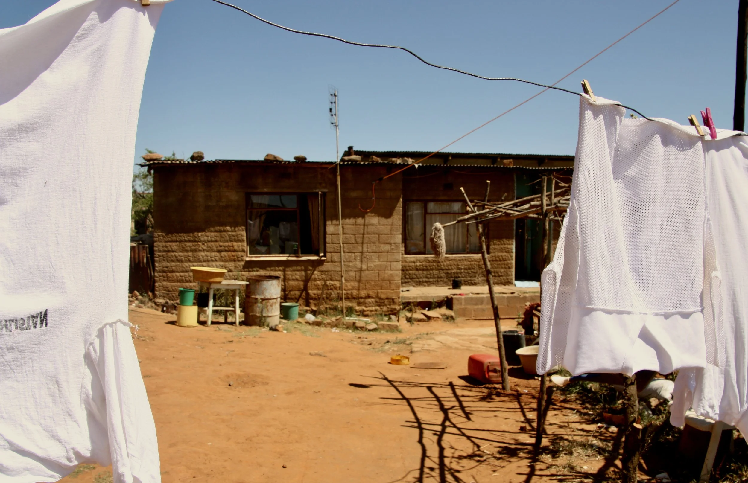 Laundry hangs outside Michael’s home in Ha Chonapase. Michael survives on a monthly pension and says most of the household income goes toward school costs, food and basic living expenses for the children he now raises alone.