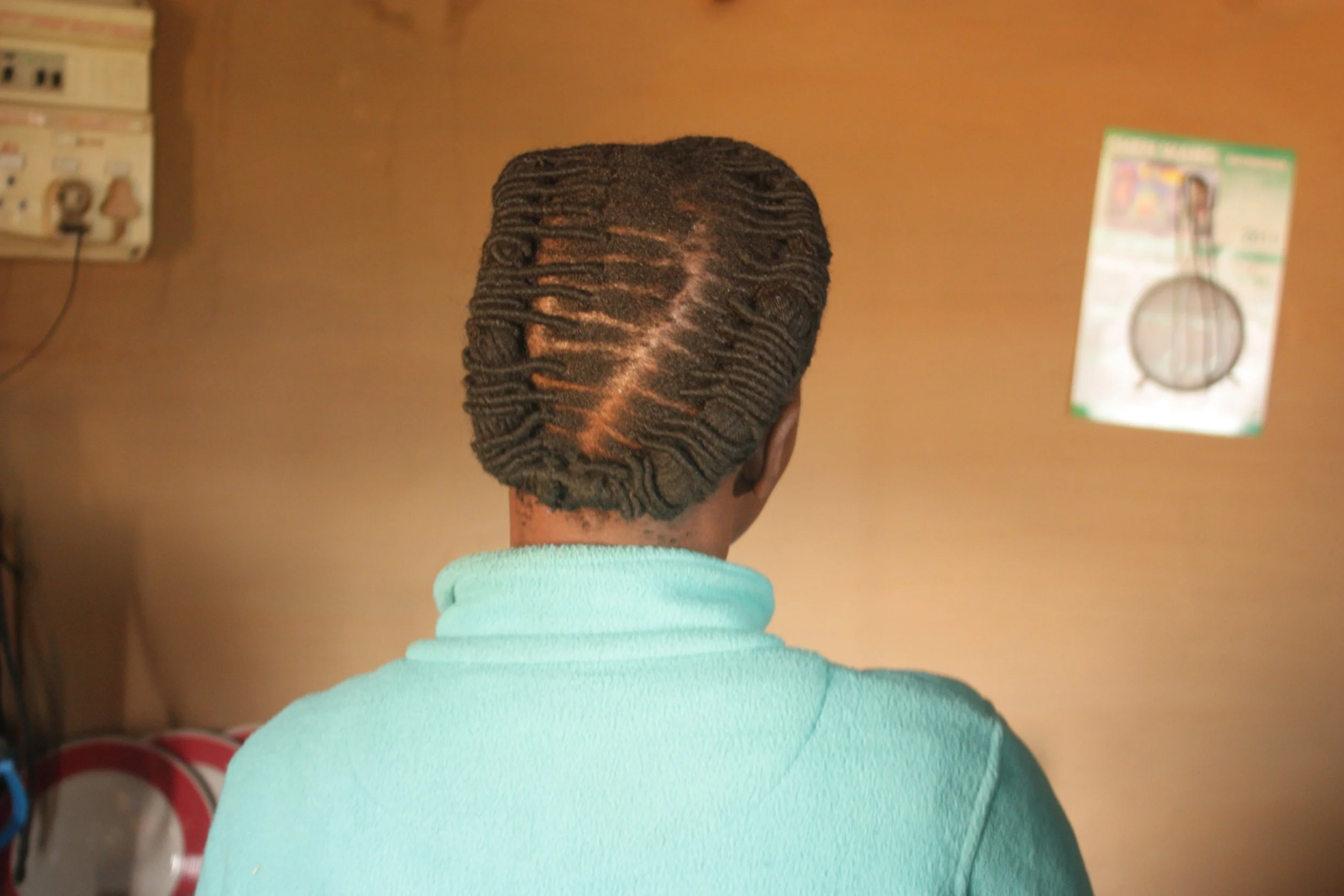 Palesa sits inside her one-room home in Thaba Moorosi, Lithipeng, where she cares for her severely disabled daughter, Lebo. The image focuses on gesture and domestic space rather than direct portraiture.