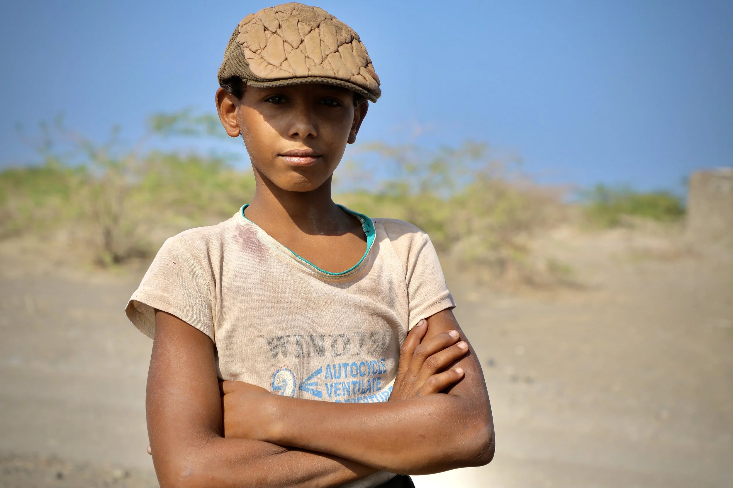 Amar’s son stands on the family’s land. Children grow up alongside fields where clearance is still ongoing.