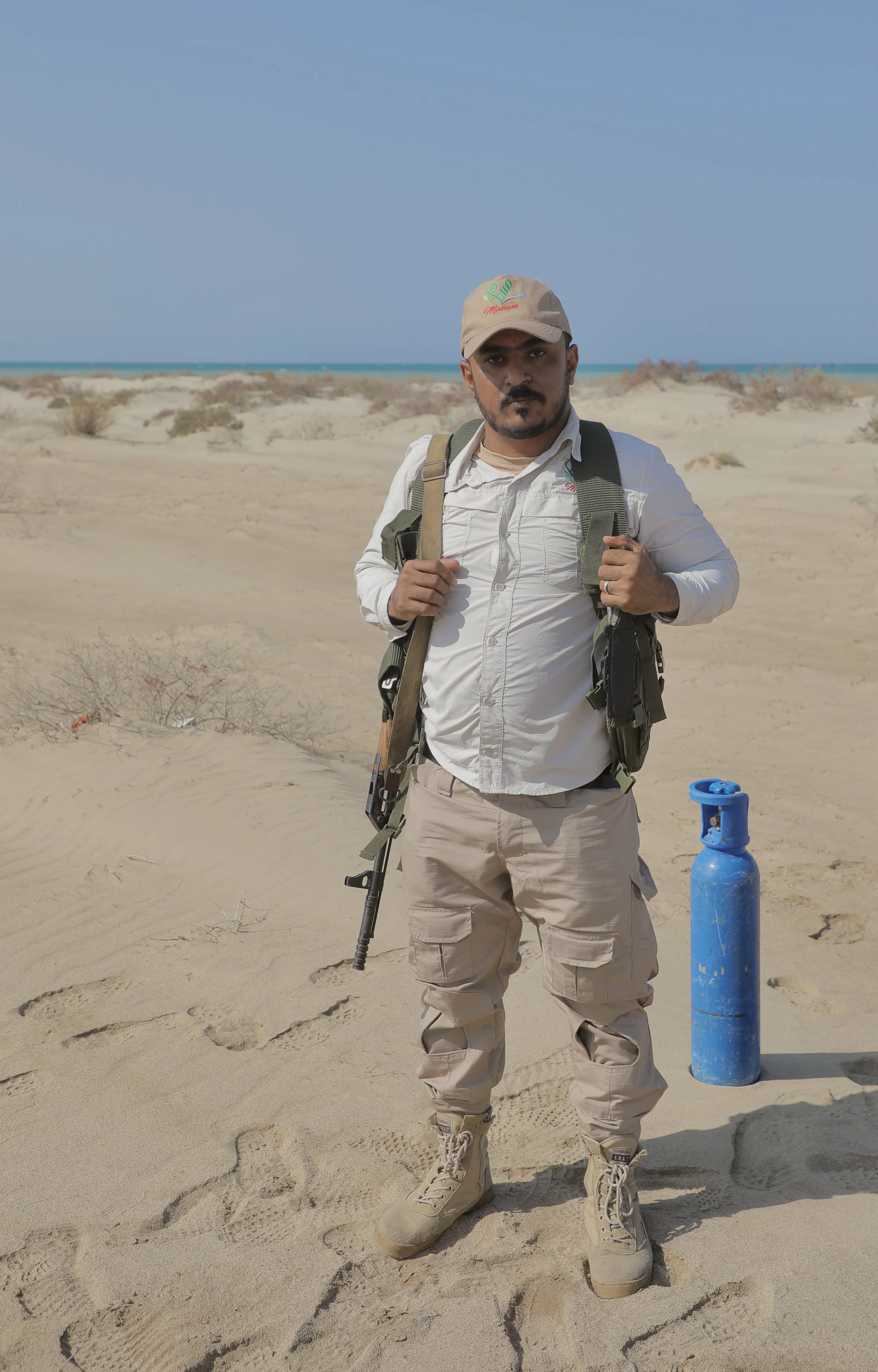 An armed security guard assigned to protect Team 26 stands watch near the minefield. Clearance teams working close to frontline areas often travel and work with armed escorts.