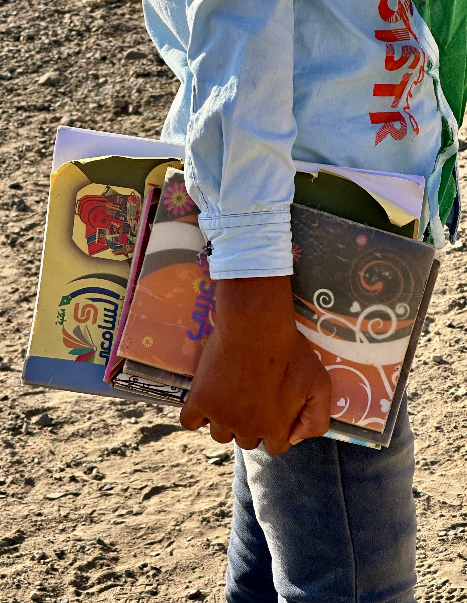 A student carries schoolbooks across the grounds of Ibrahim Aqeel School in Taiz. Many children at the school lost years of education because of conflict, displacement, and landmine contamination.