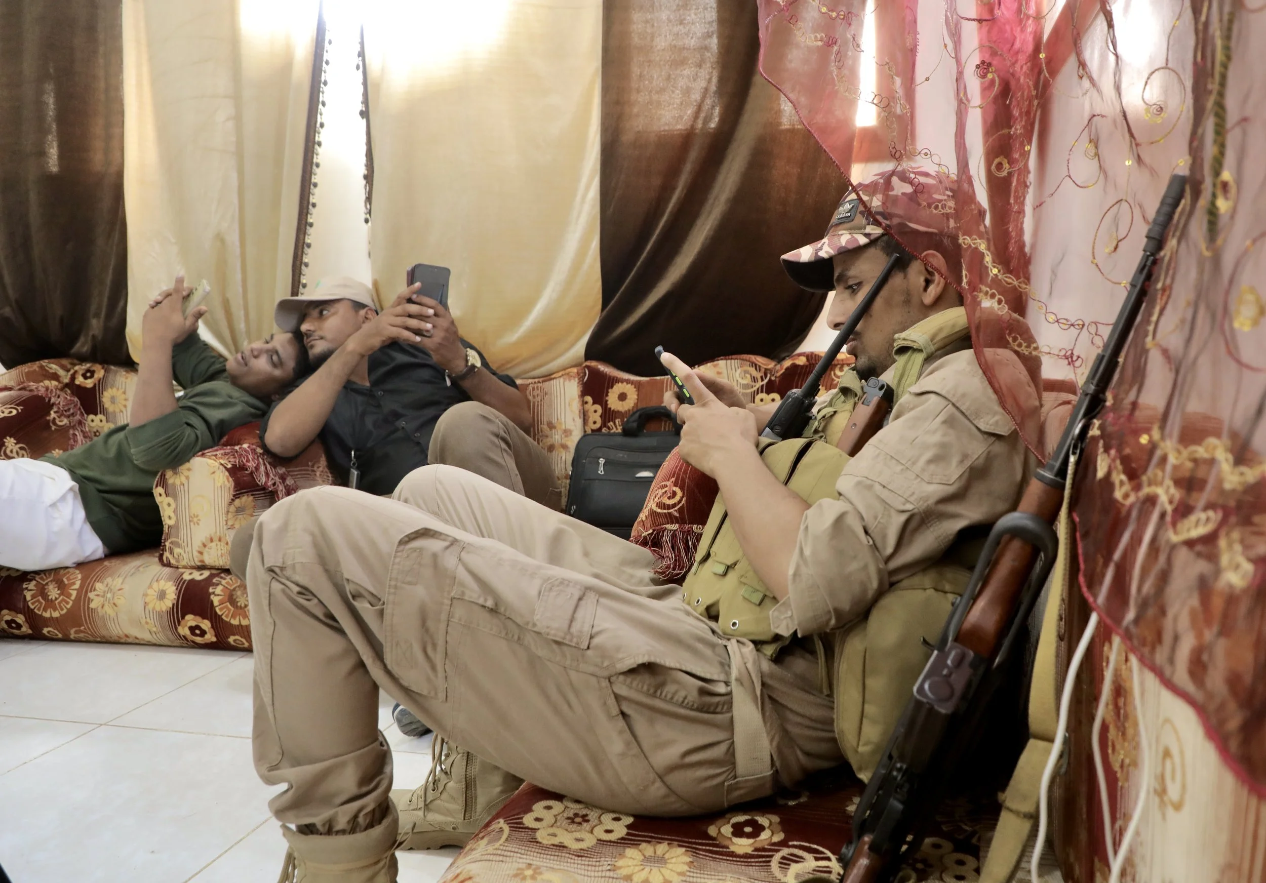 Security guards rest inside the family home after returning from the field. Weapons remain a constant presence, even within domestic spaces close to the frontlines.