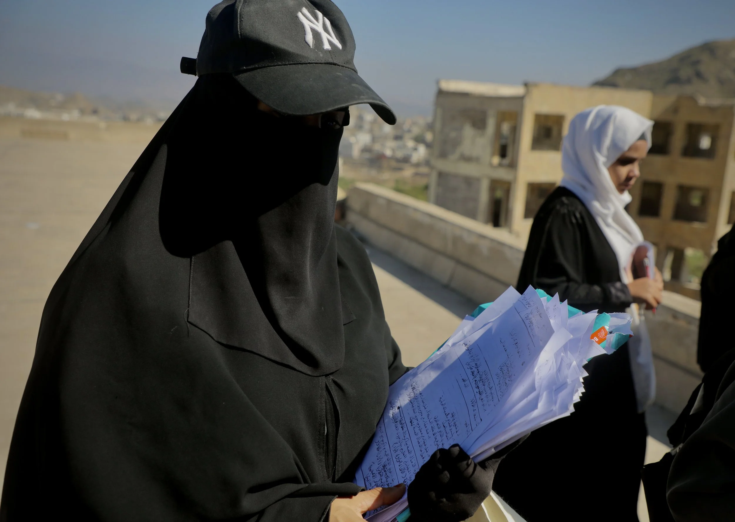 A teacher carries exam papers after collecting them from students during rooftop exam sessions at Ibrahim Aqeel School in Taiz, Yemen.