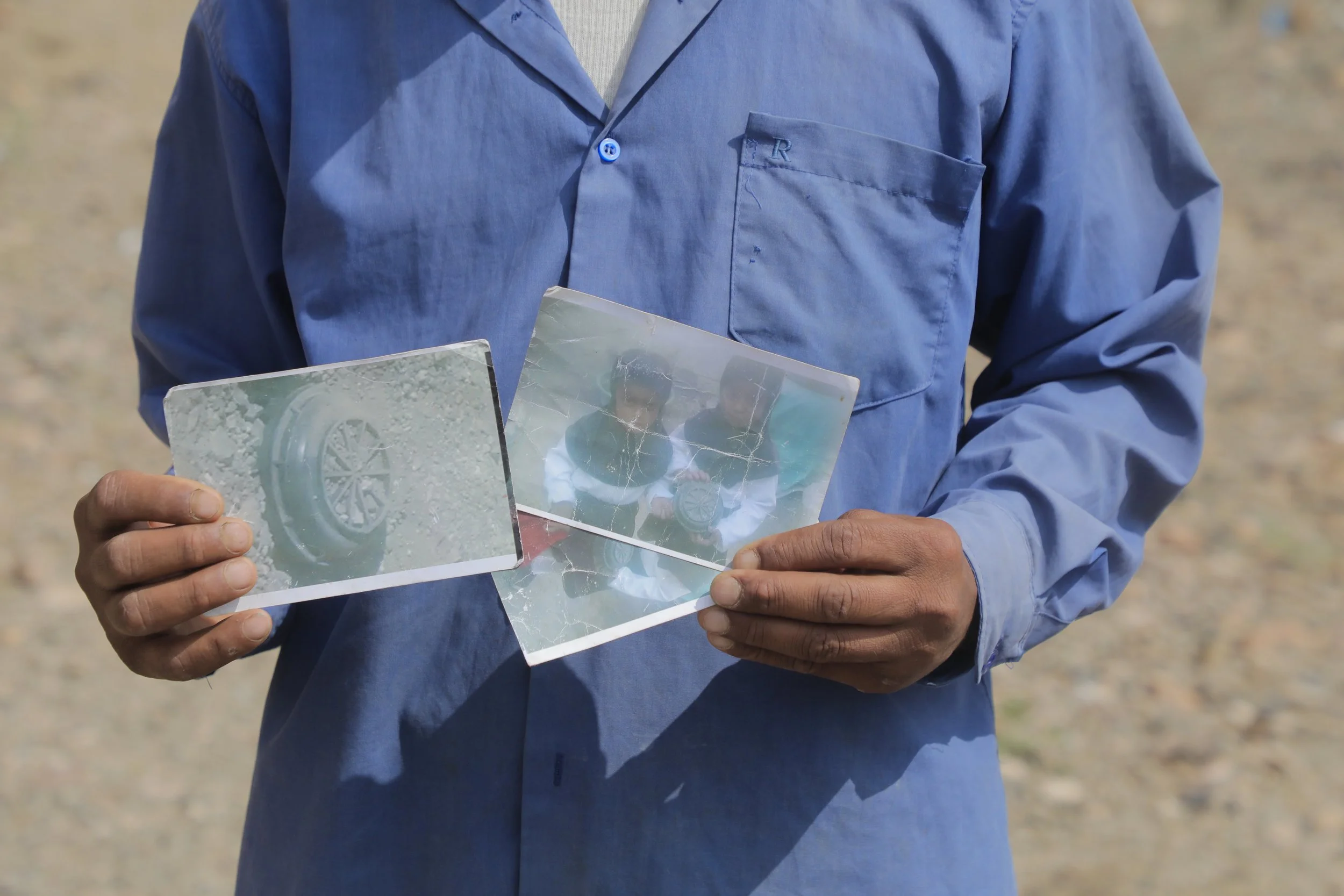 Radwan Mohammed holds the photographs he took when his daughters Ilham, 7, and Iman, 5, discovered anti-personnel landmines while playing marbles outside their home, Al Jadanah village, Shakhab, Al Dhale. The photographs - cracked and worn from handl