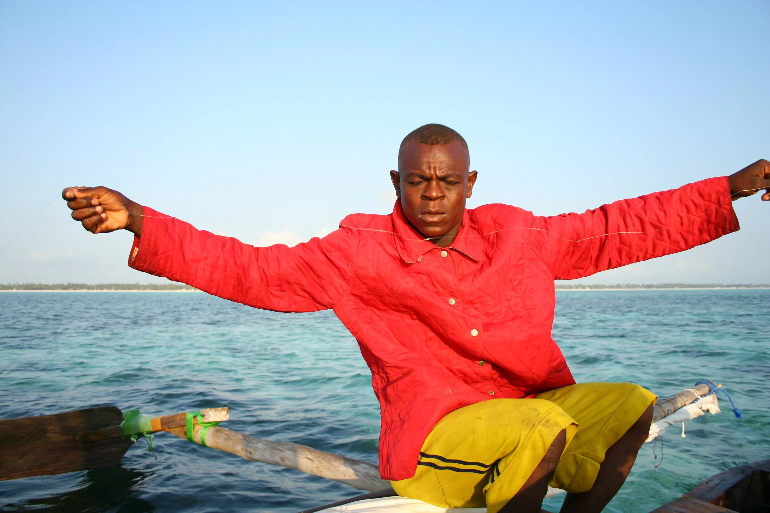 Captain Fruit works a hand line taut between both hands, eyes closed in concentration against the glare off the water.