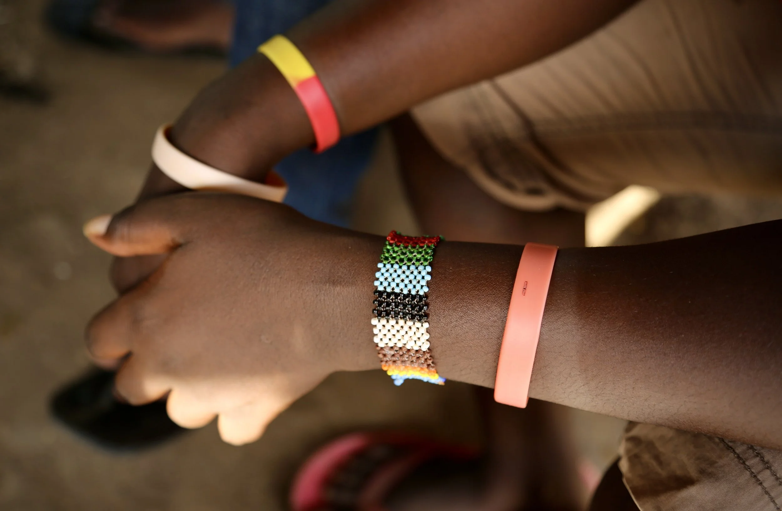 Bracelets worn by Mary include colours associated with LGBTQ+ identity and solidarity inside the camp.