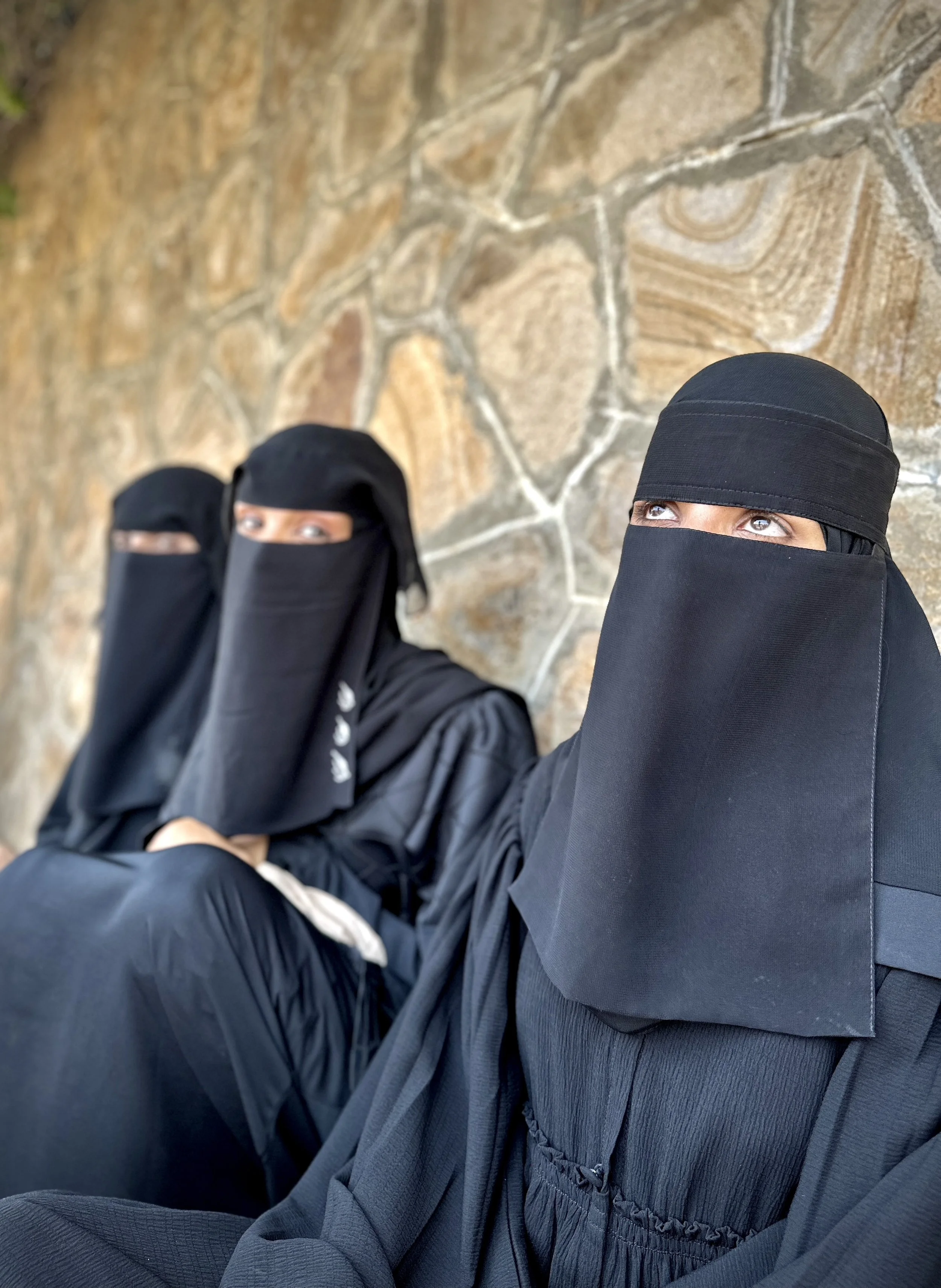 Explosive Ordnance Risk Educators Sara Abdulwahab Baggash (foreground right) and Boshra Mohammed (centre) wait for transport after completing a community awareness session in Taiz, Yemen. The educators, who work with the Yemen Executive Mine Action C