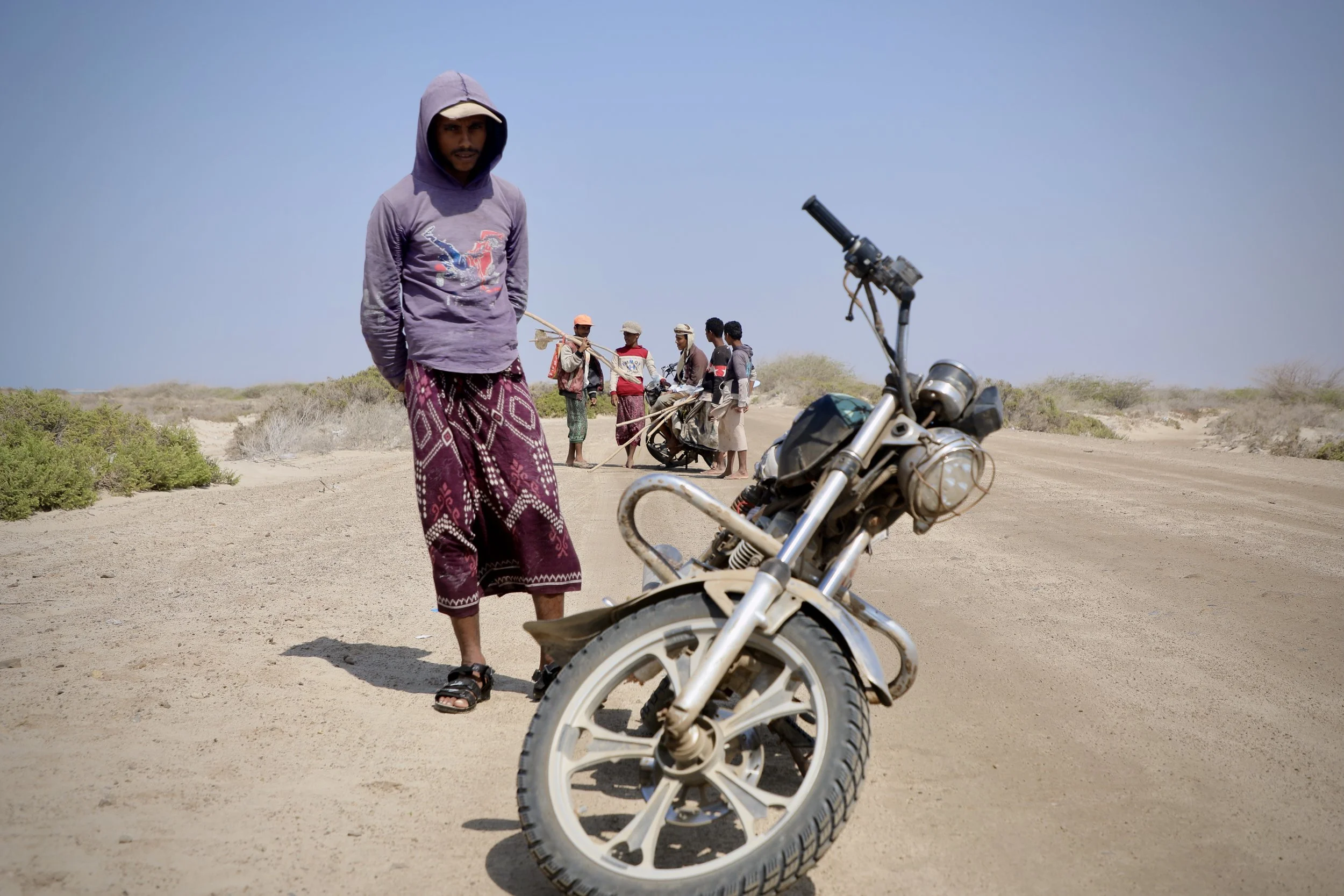 A teenager stands beside a motorcycle used by fishermen travelling between isolated coastal communities along Yemen’s west coast, where many families have been displaced by mines and conflict.