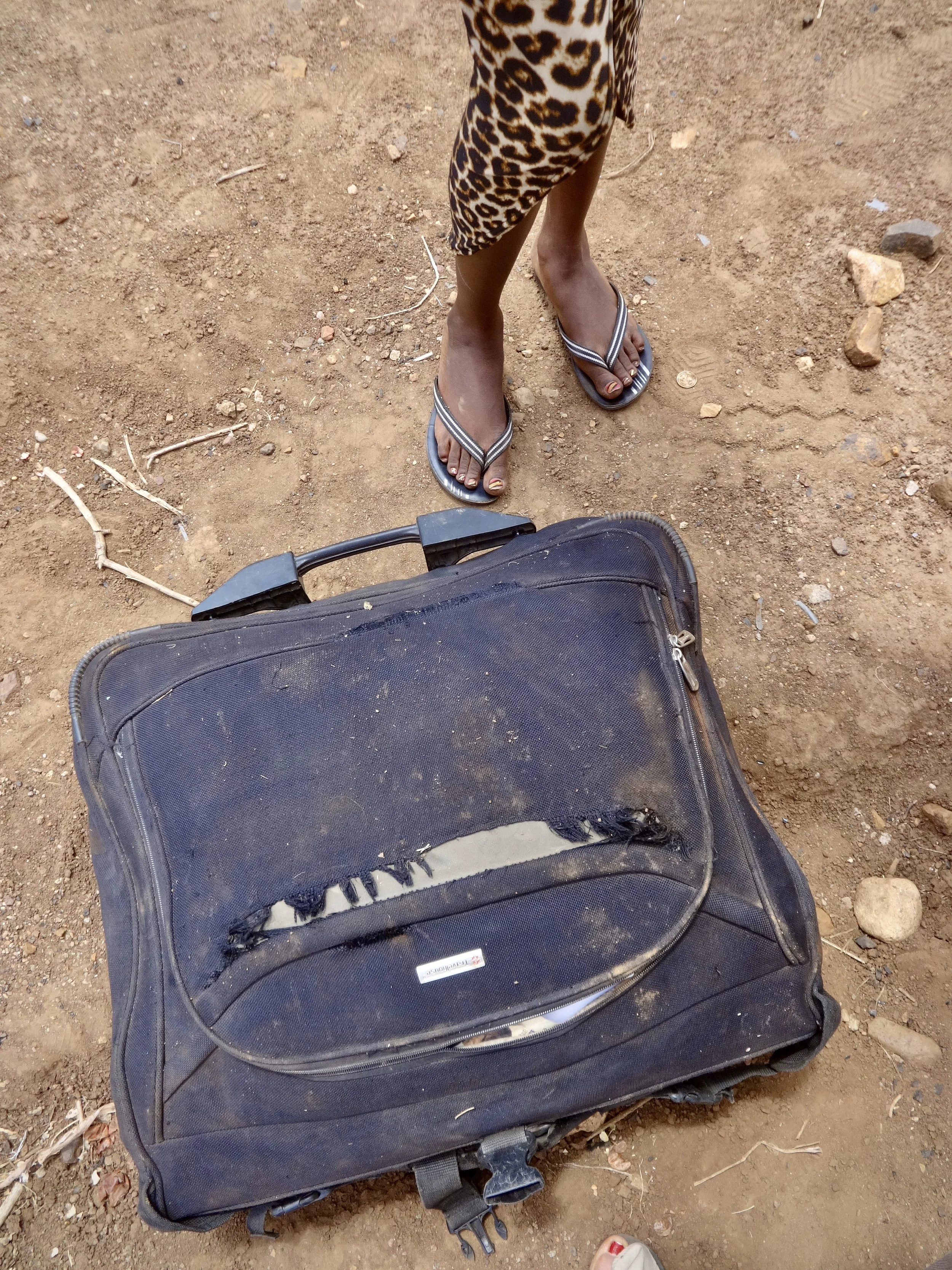 A suitcase lies on the ground beside Randa. With limited resources, many asylum seekers arrived at the border with only what they could carry.