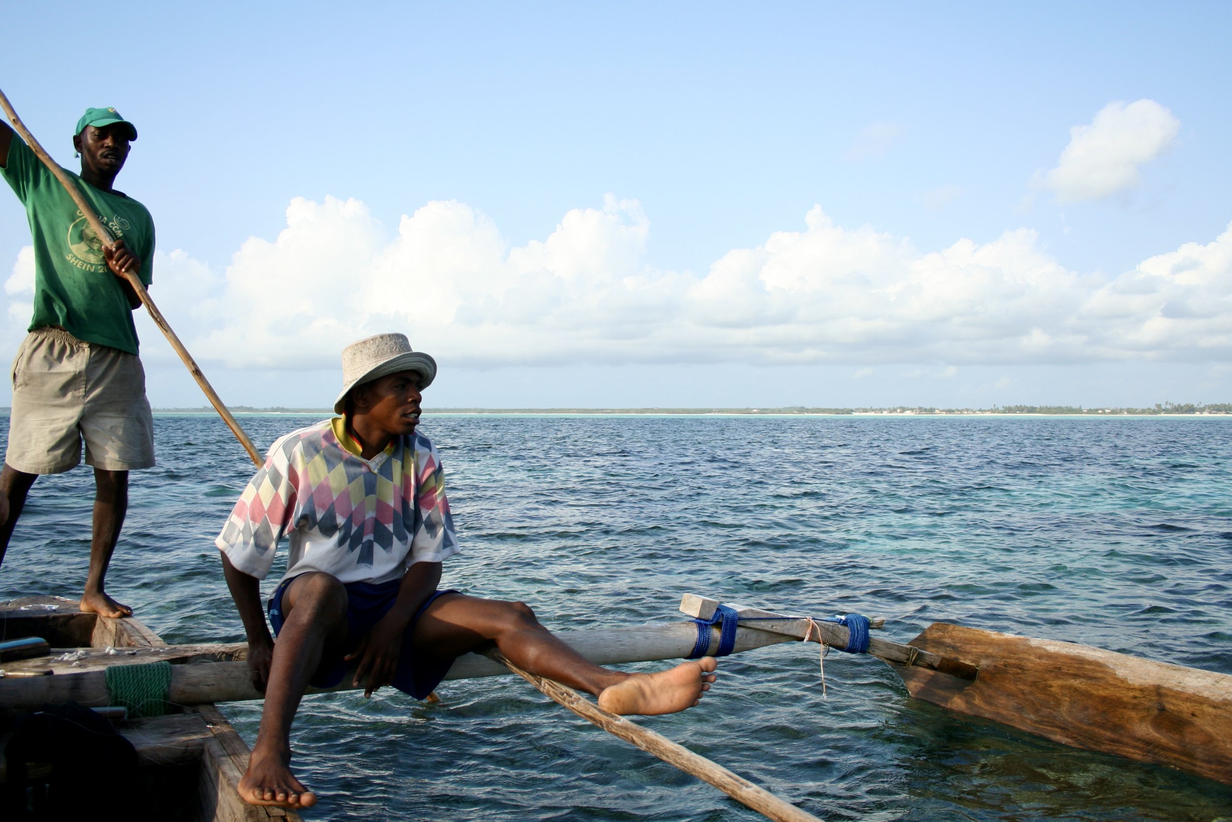 The dhow's outrigger holds steady against the current as Jambiani's white-sand coastline stretches behind it.