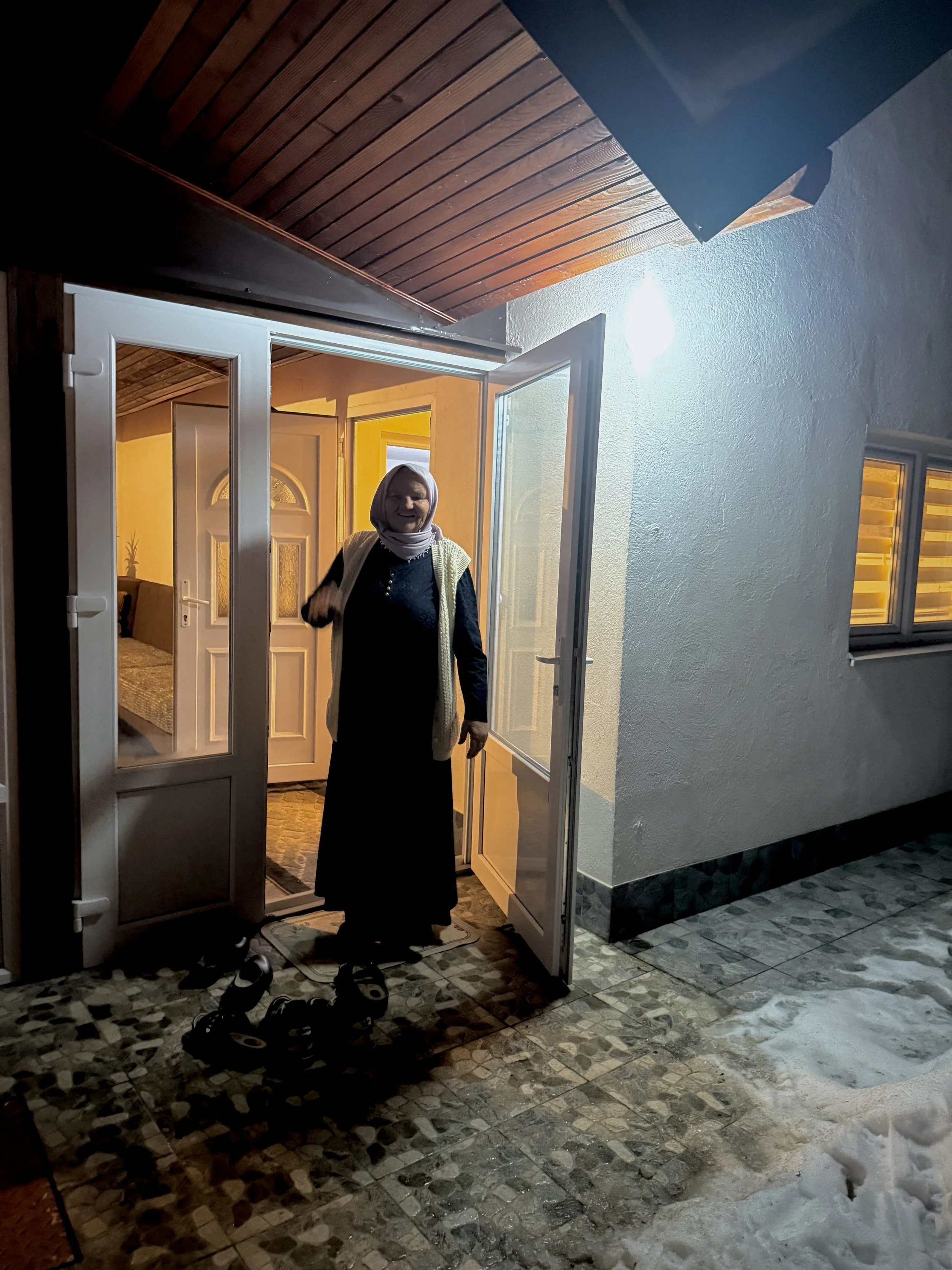 Saliha Osmanović standing in the doorway of her home in Dobrak, Bosnia and Herzegovina, on a winter evening.
She returned to the family house after the war, saying she felt closer to her husband and sons there, and could still dream of them coming ho