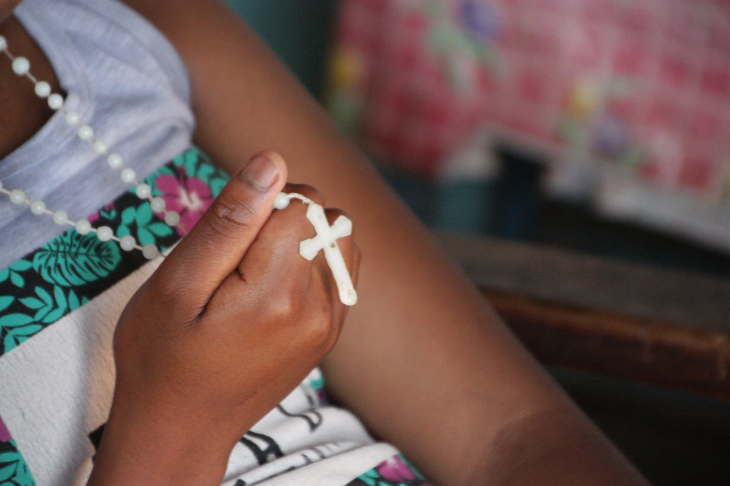 Beauty, 14, holds a rosary. A deeply religious family, Beauty hopes and prays she will one day run her own business.