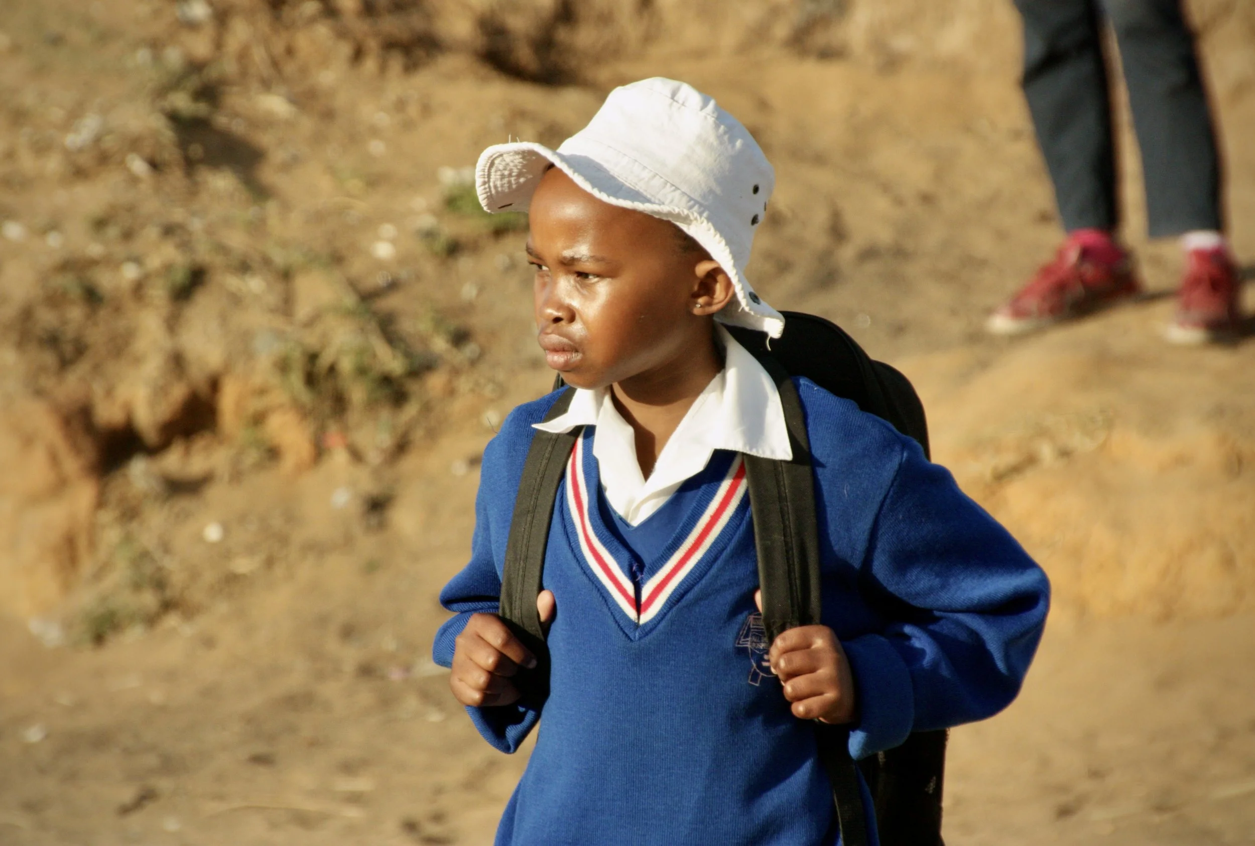 A neighbour's child walks to school near Michael's home in Leribe District. Michael says keeping his grandchildren in school is his greatest concern as rising costs and disputes over bursary payments threaten his granddaughter's education. 