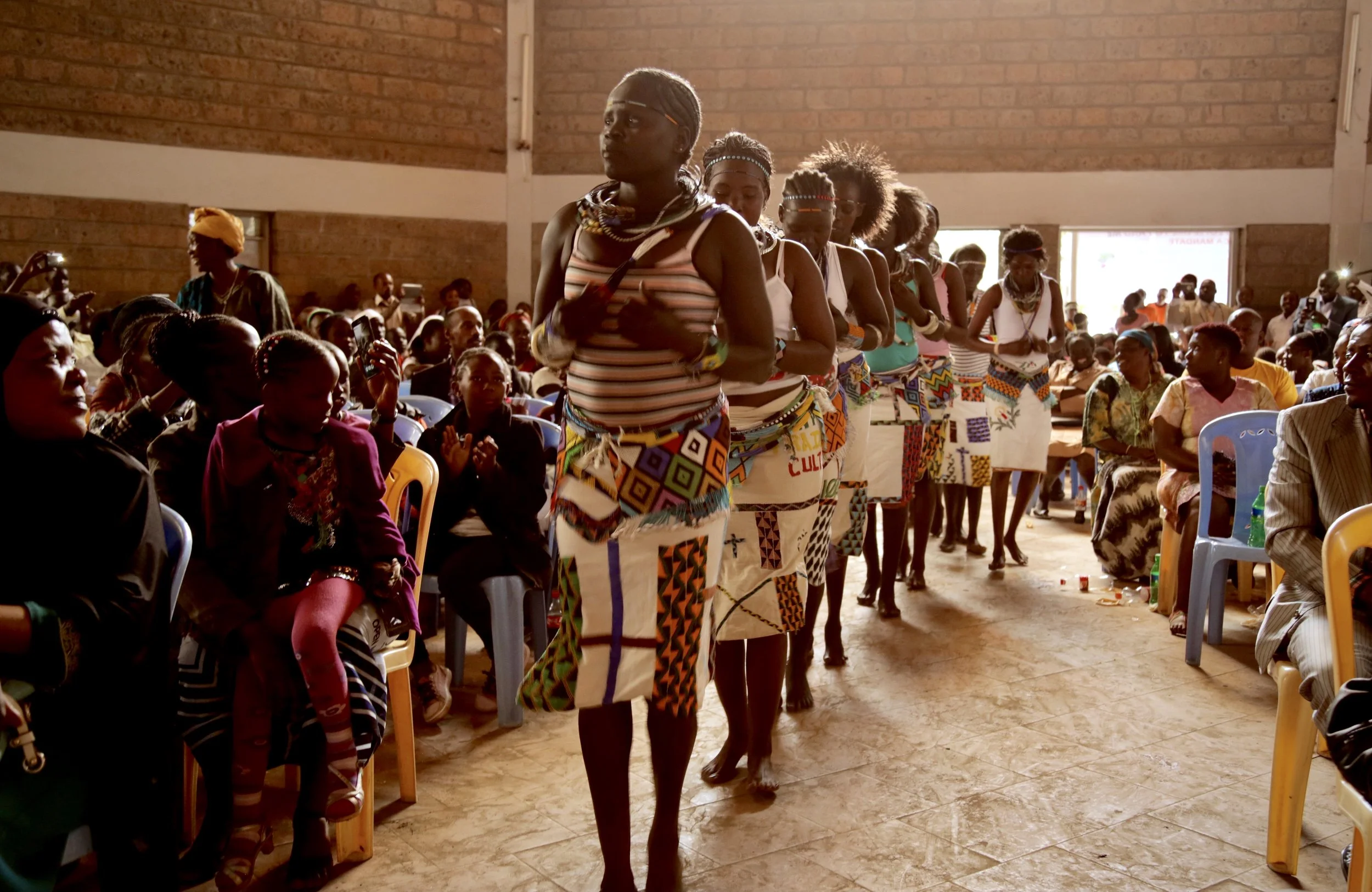 Refugee performers process through the church as audience members watch and applaud during World Refugee Day celebrations in Nairobi.