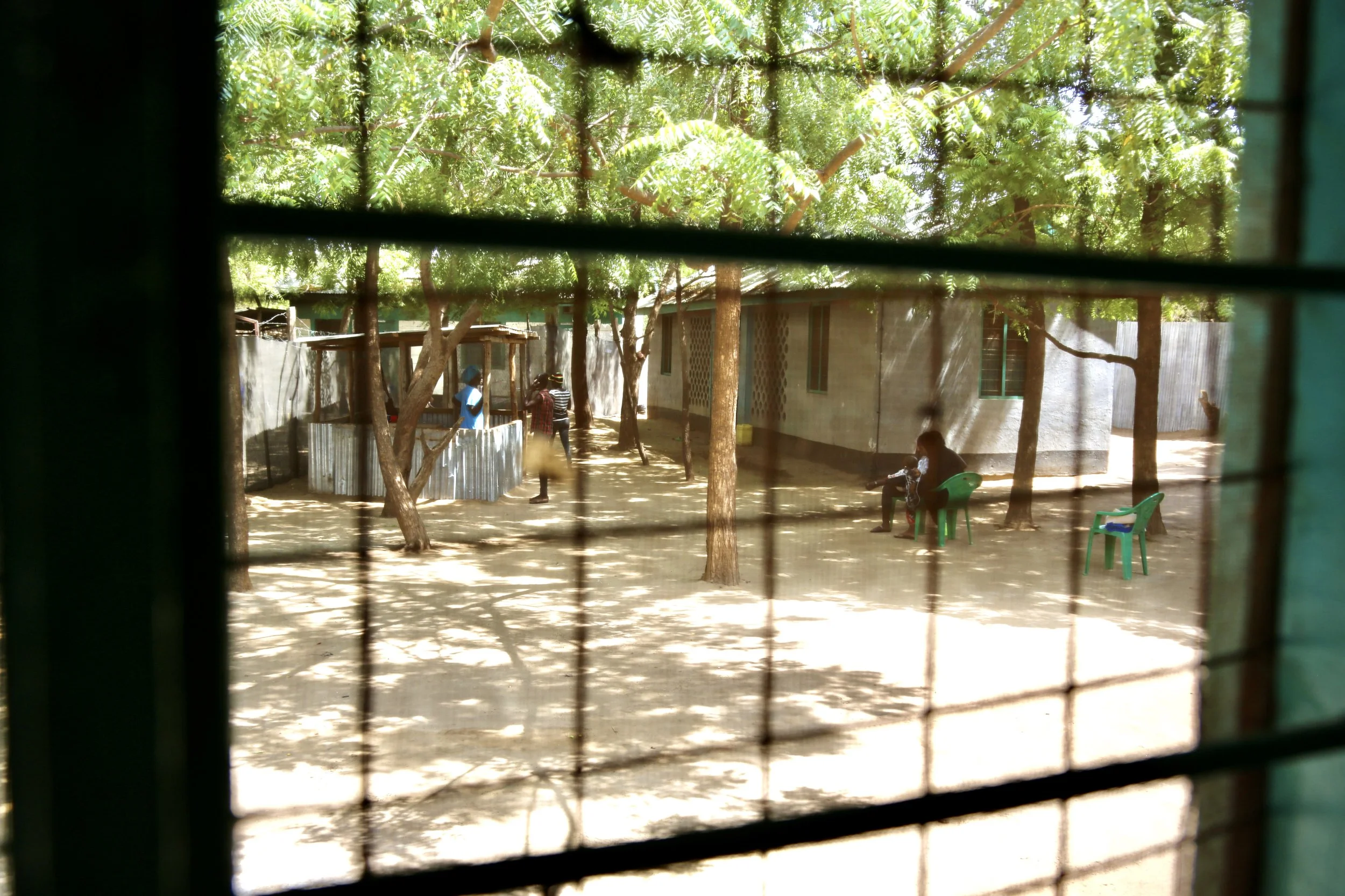 Viewed through barred windows, the shelter courtyard is seen beyond the room where residents lived. Security measures shaped daily life for women under threat.