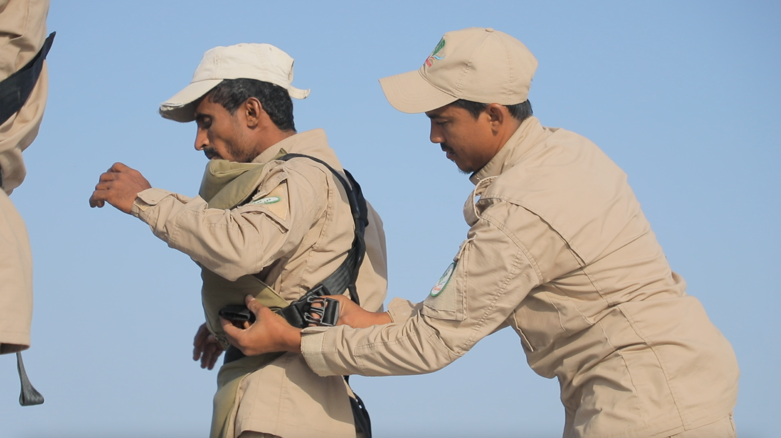 Sami helps another team member adjust protective equipment before entering the minefield.