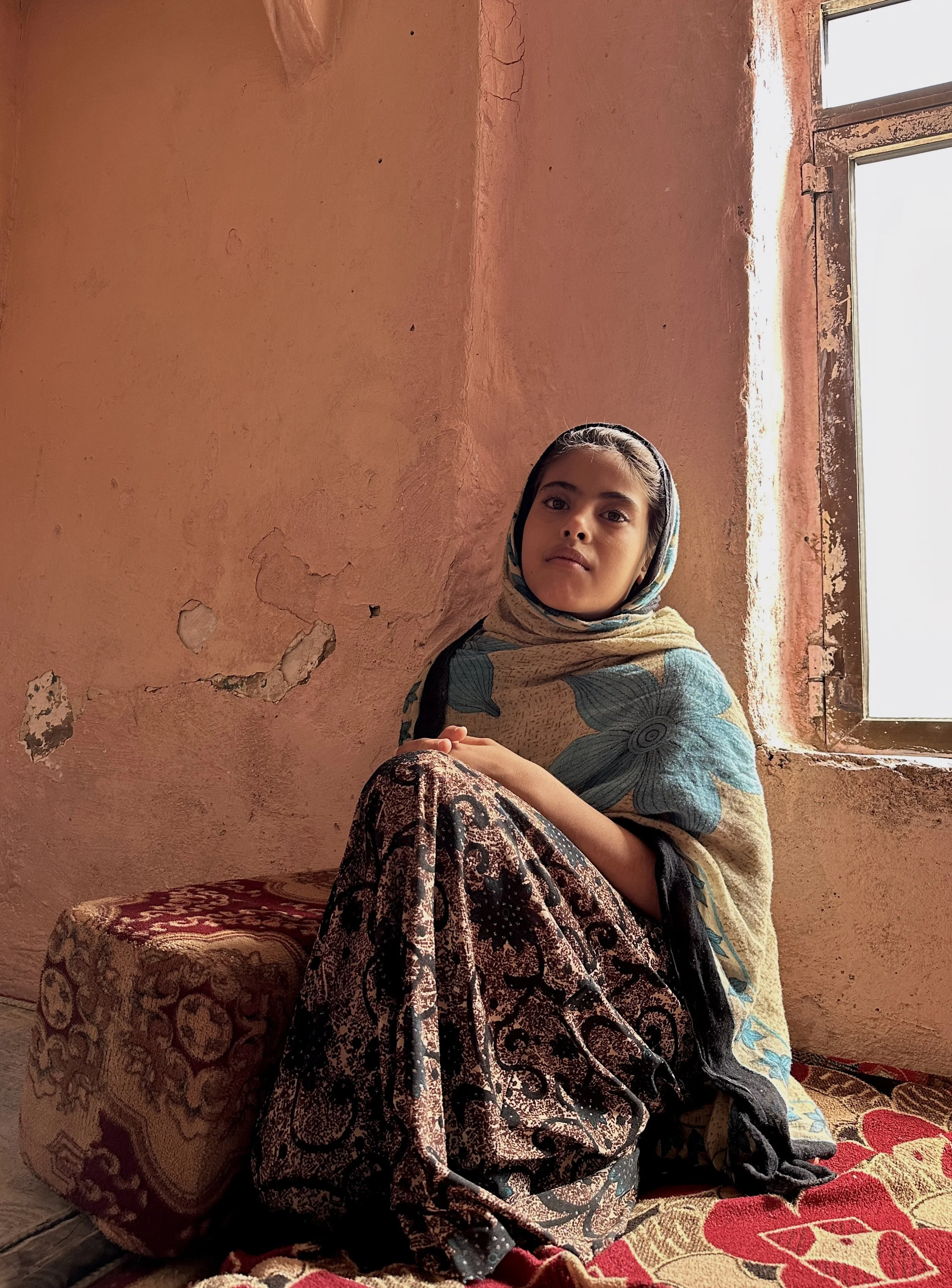 A young relative of Dalila Abdo Ahmed sits near a window inside the family apartment in Taiz. Despite repeated tragedy and displacement, Dalila’s family remains closely connected and supportive.
