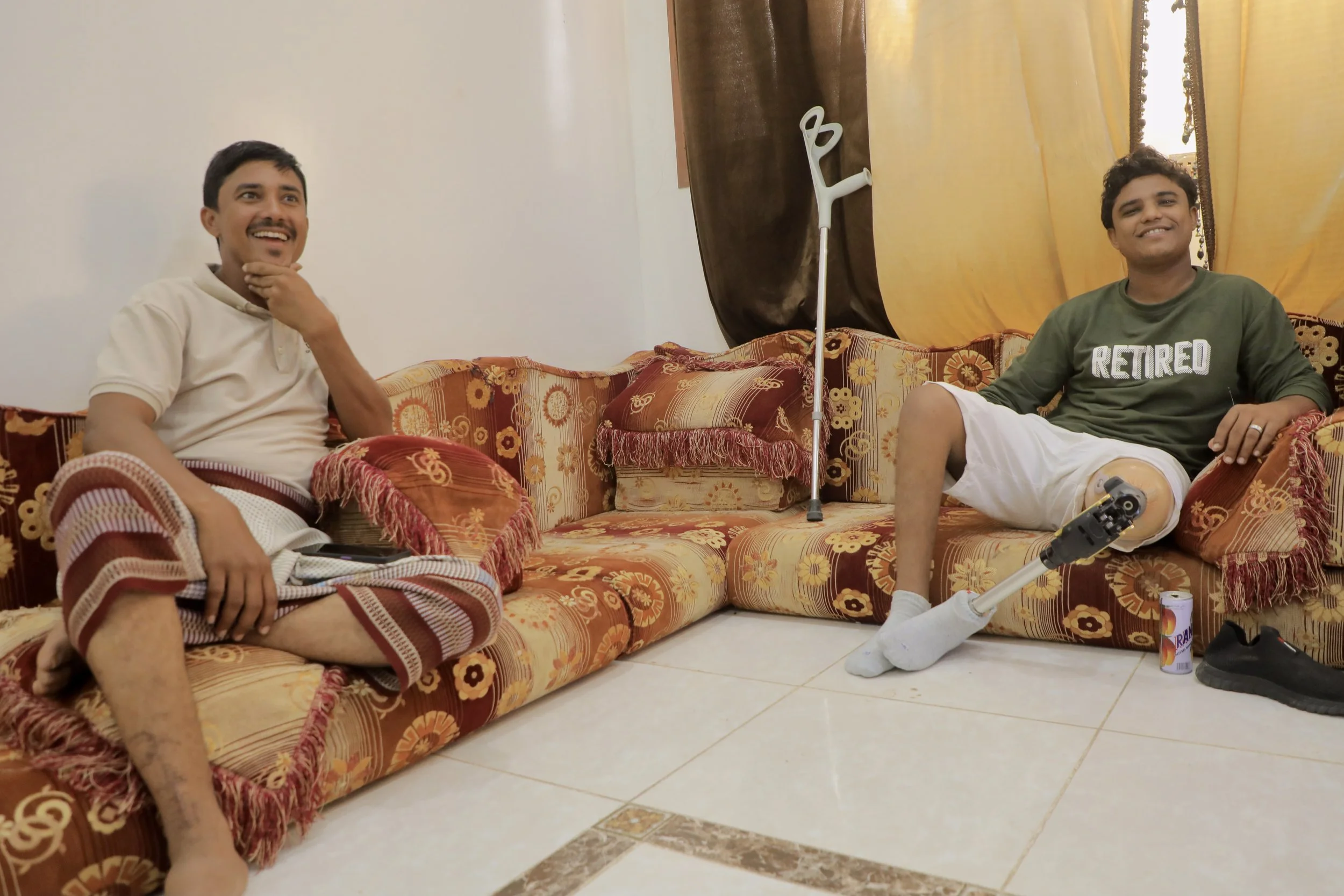 After returning from the minefield and changing clothes, Sami Haimed discusses the day’s clearance work with his older brother Mohammed, a former deminer who lost his leg in a landmine accident. Mohammed’s prosthetic leg and crutch rest between them 