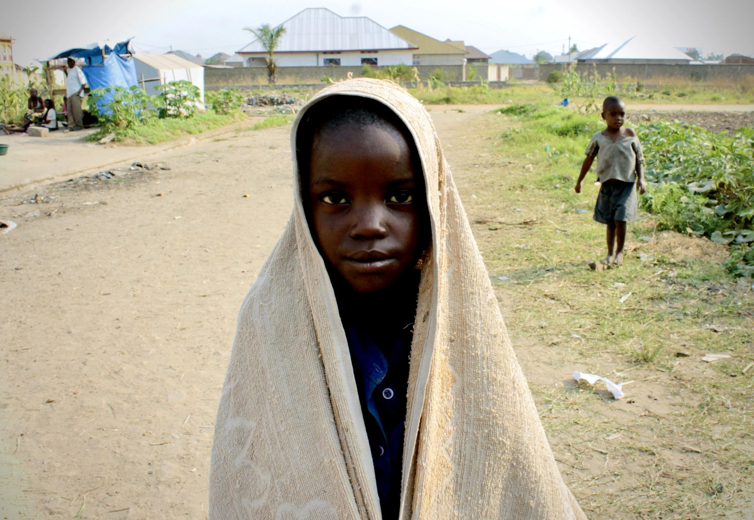A child wrapped in cloth stands on a pathway inside the displaced persons camp, where families uprooted by Burundi’s 2015 political crisis sought safety in makeshift shelters.