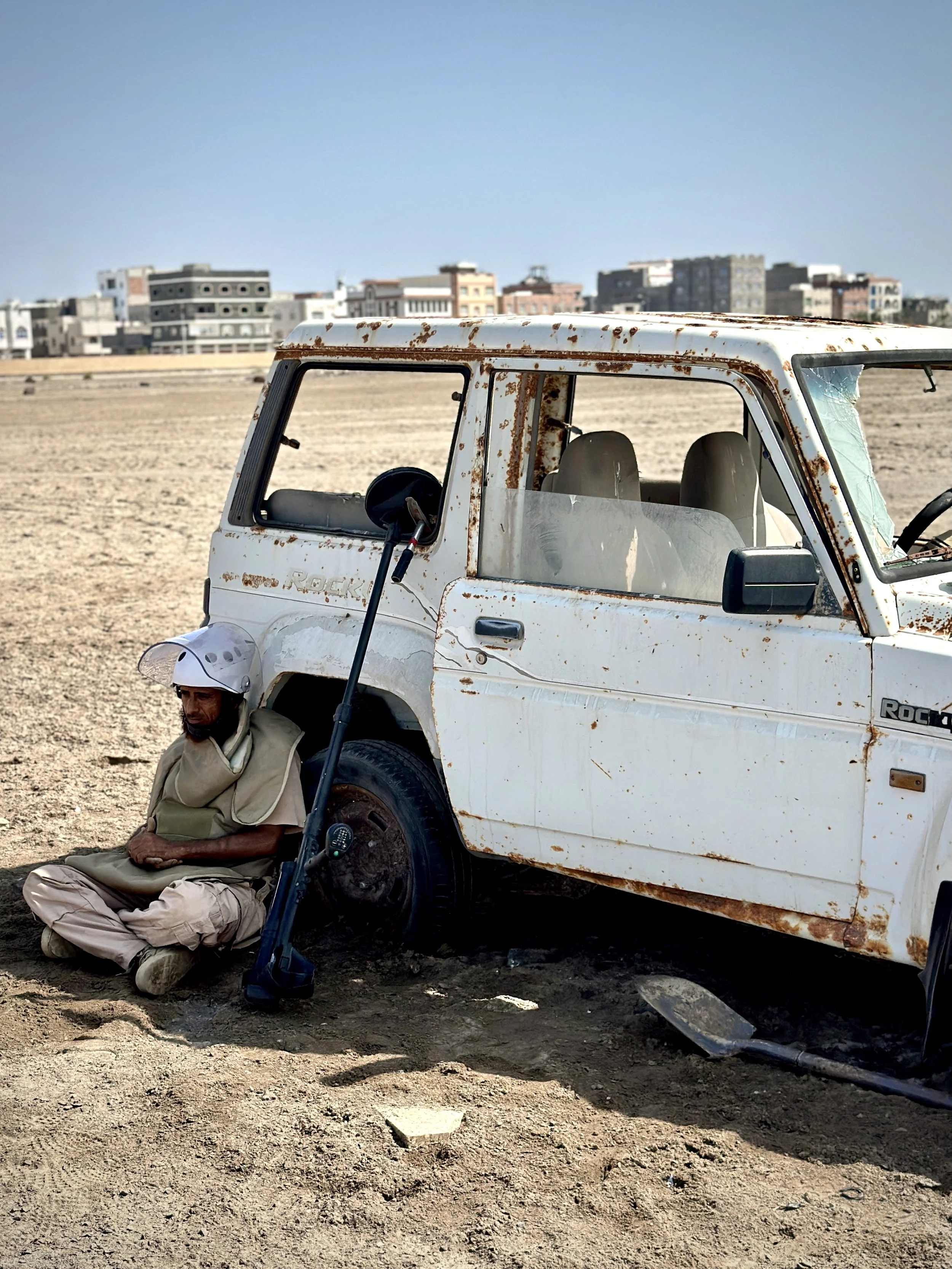 A burned-out vehicle remains inside Aden International Airport, where wreckage and debris still mark past battles. Deminers say abandoned machinery, twisted metal and disturbed earth can make clearance work more complex.