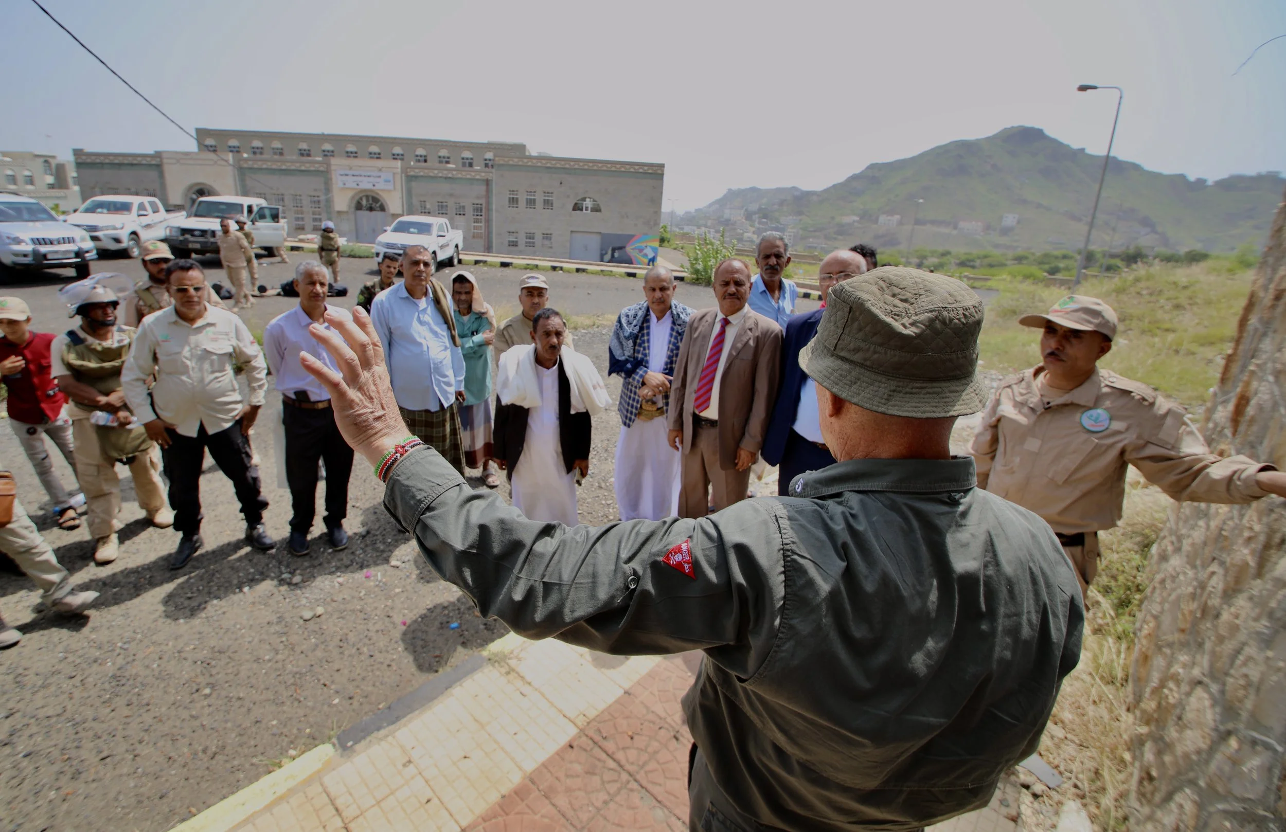 Residents, local officials and demimers gather around Deon von Landsberg, Training Adviser and Training Officer at Project Masam, during a community awareness session in Sabr Almawadim, western Taiz, Yemen. Public awareness campaigns are a key compon
