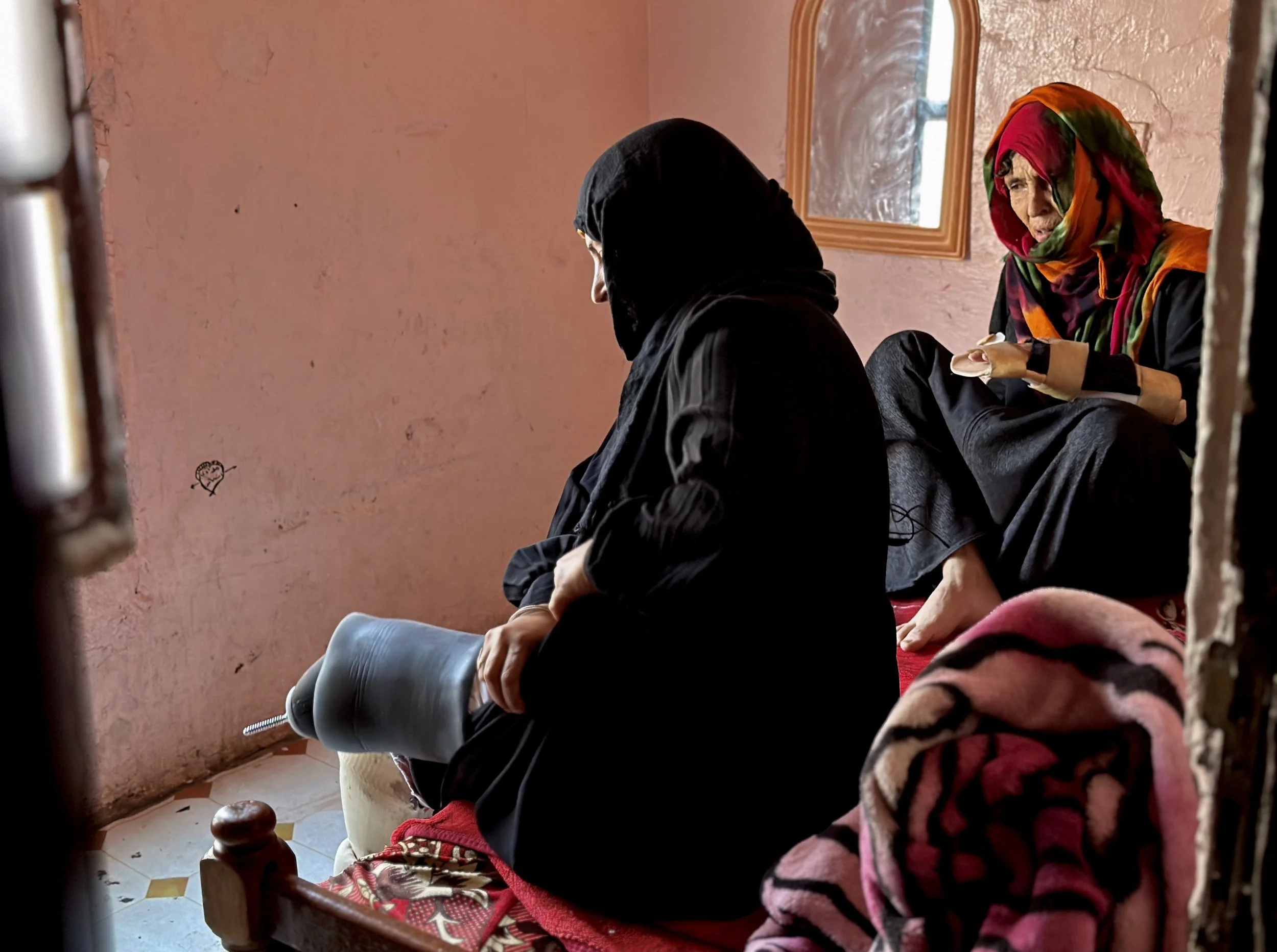 Qoboul Ahmed Al-Hajj watches as her daughter Dalila Abdo Ahmed fits one of her prosthetic limbs inside their apartment in Taiz. Despite repeated losses during the war, Qoboul says she still hopes for a better future for her family.