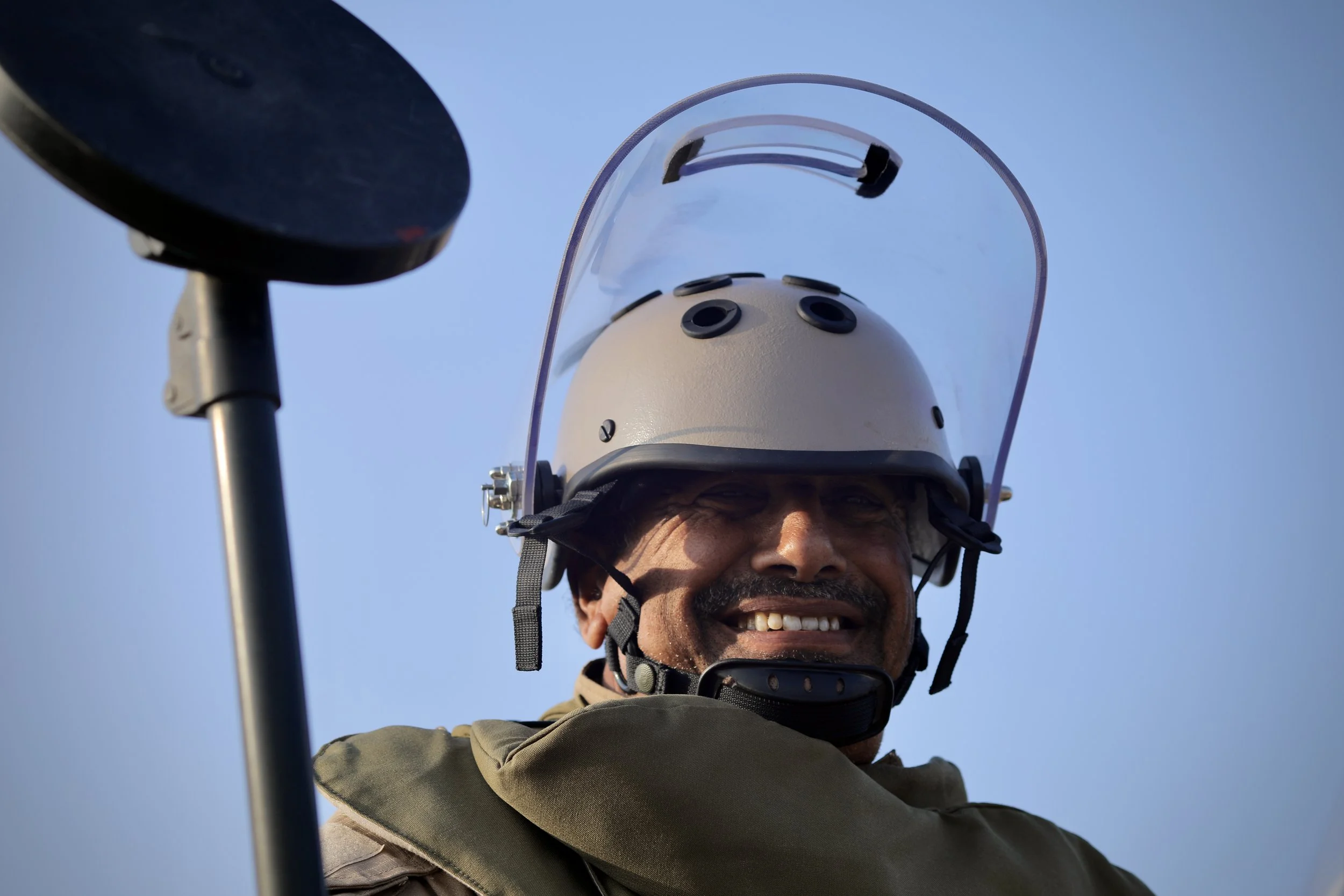 A deminer from Team 21 smiles after returning to the Control Point at the end of a shift in Al Remah, near Mocha, Taiz governorate, Yemen. Protective equipment is only removed once deminers exit the clearance lane.