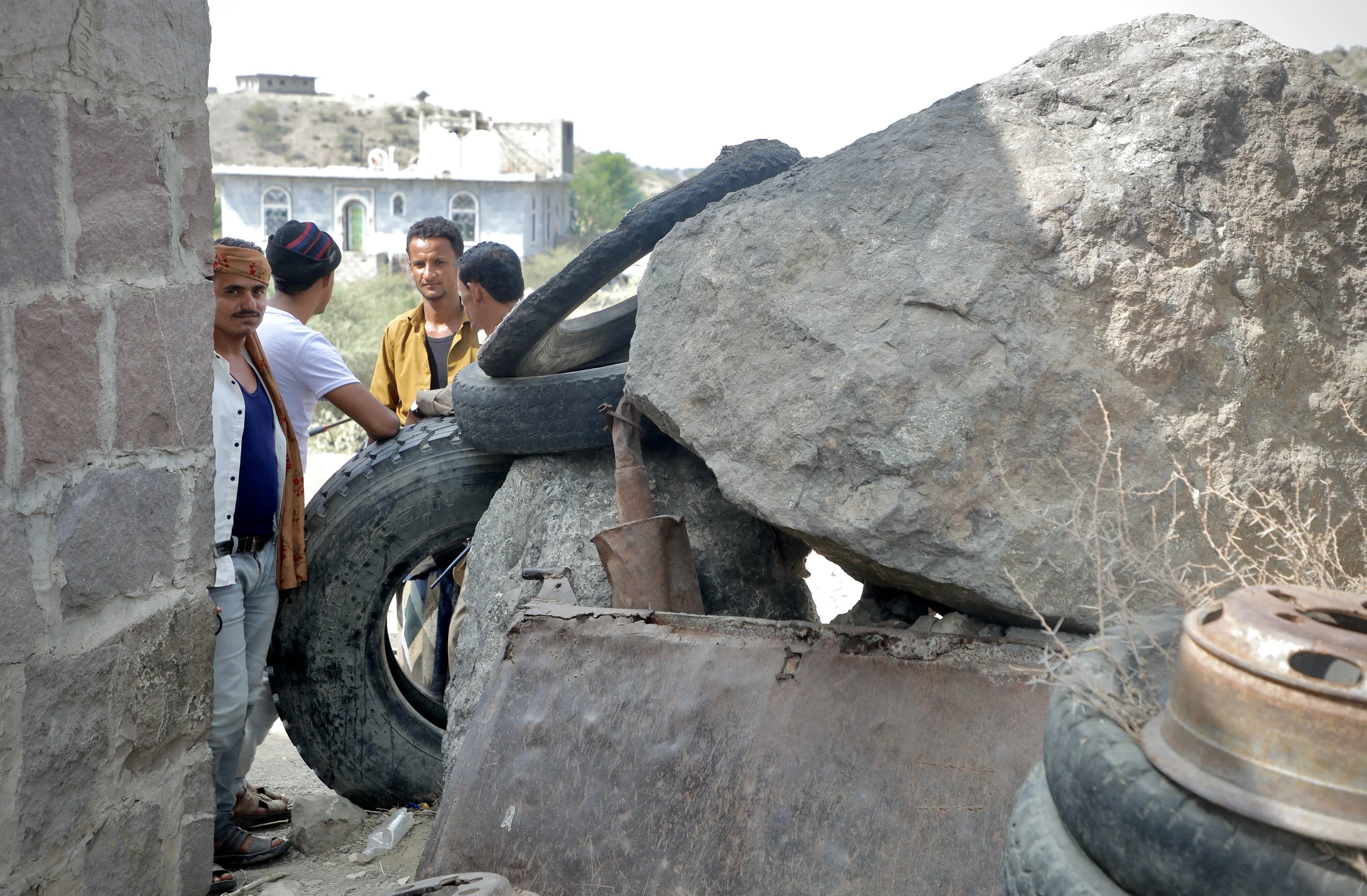 Community members beside the defensive perimeter outside the home of Mosaid Mohammed Ali Naji, Shakhab, Al Dhale. The barrier - constructed from boulders, vehicle parts and tyres - was built by local men to protect the property against potential futu