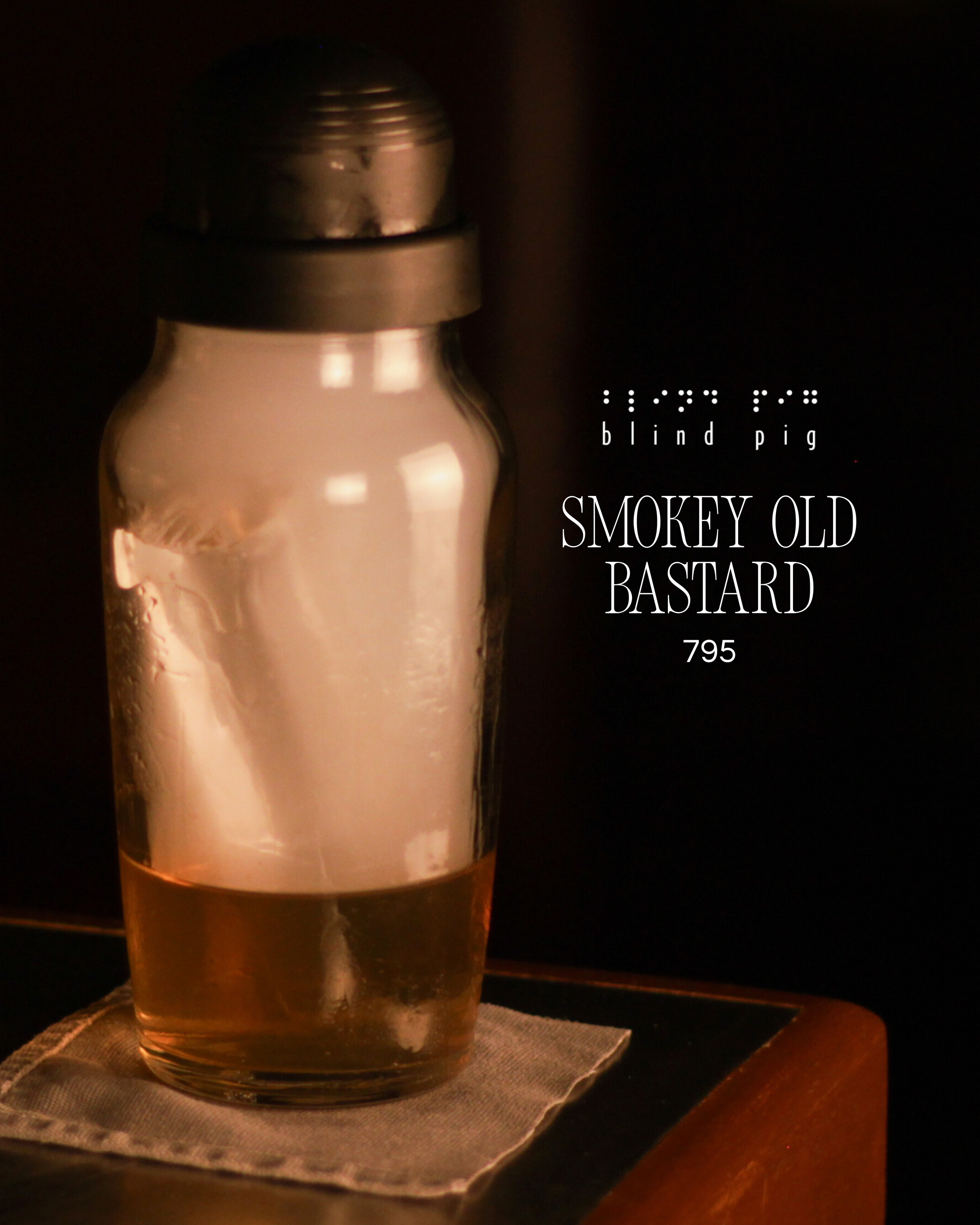 A glass bottle with a metallic cap placed on a white cloth on a dark wooden surface.