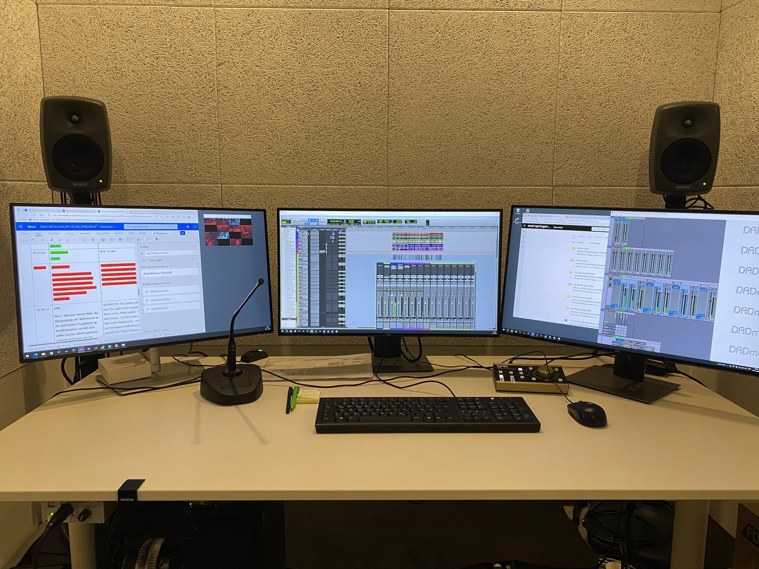 A computer workstation with three monitors displaying audio editing software and text documents, a keyboard, mouse, and studio speakers, set against a textured beige wall.
