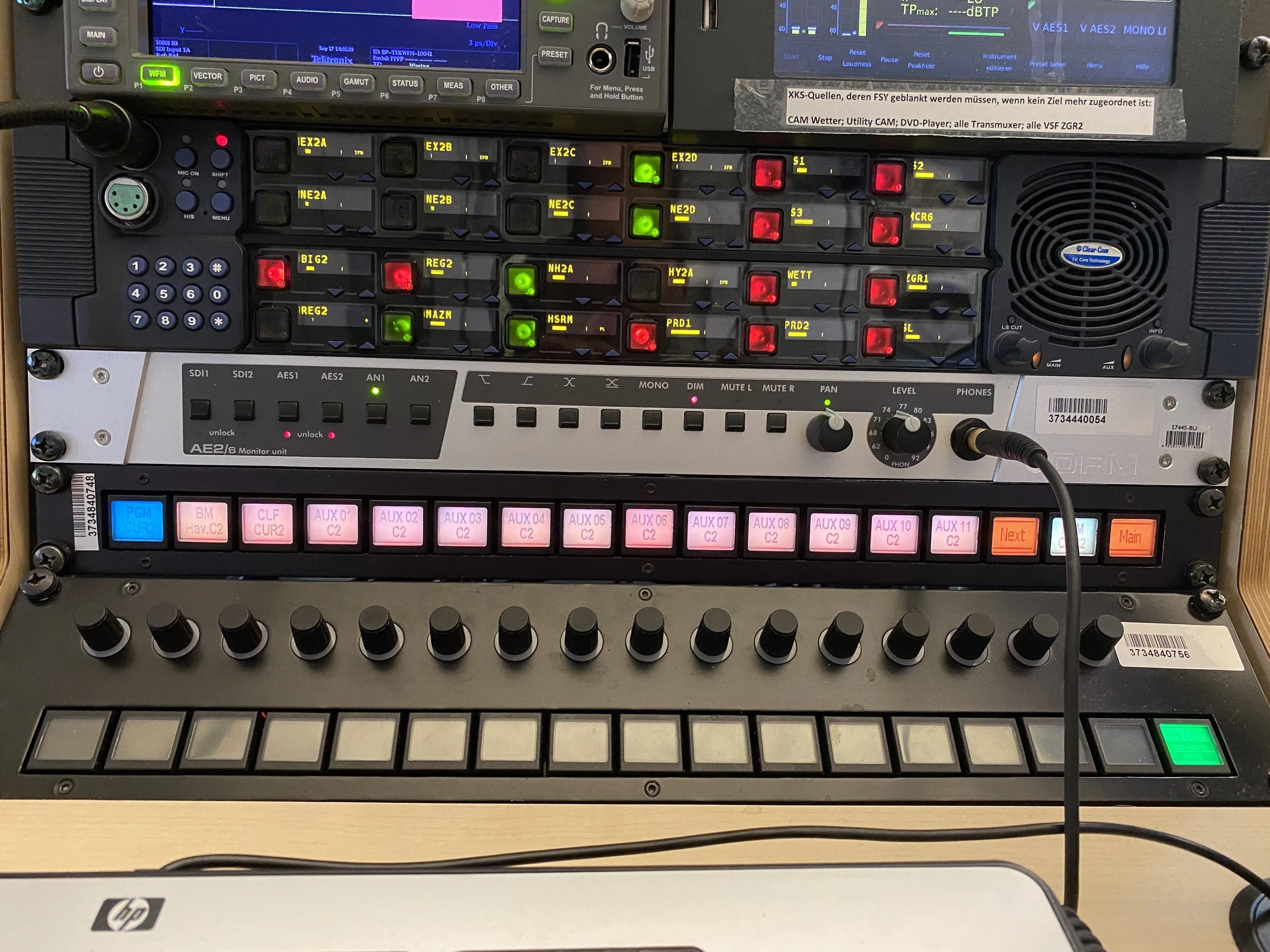Close-up of a professional audio/video control rack with various buttons, switches, and screens for managing media equipment.